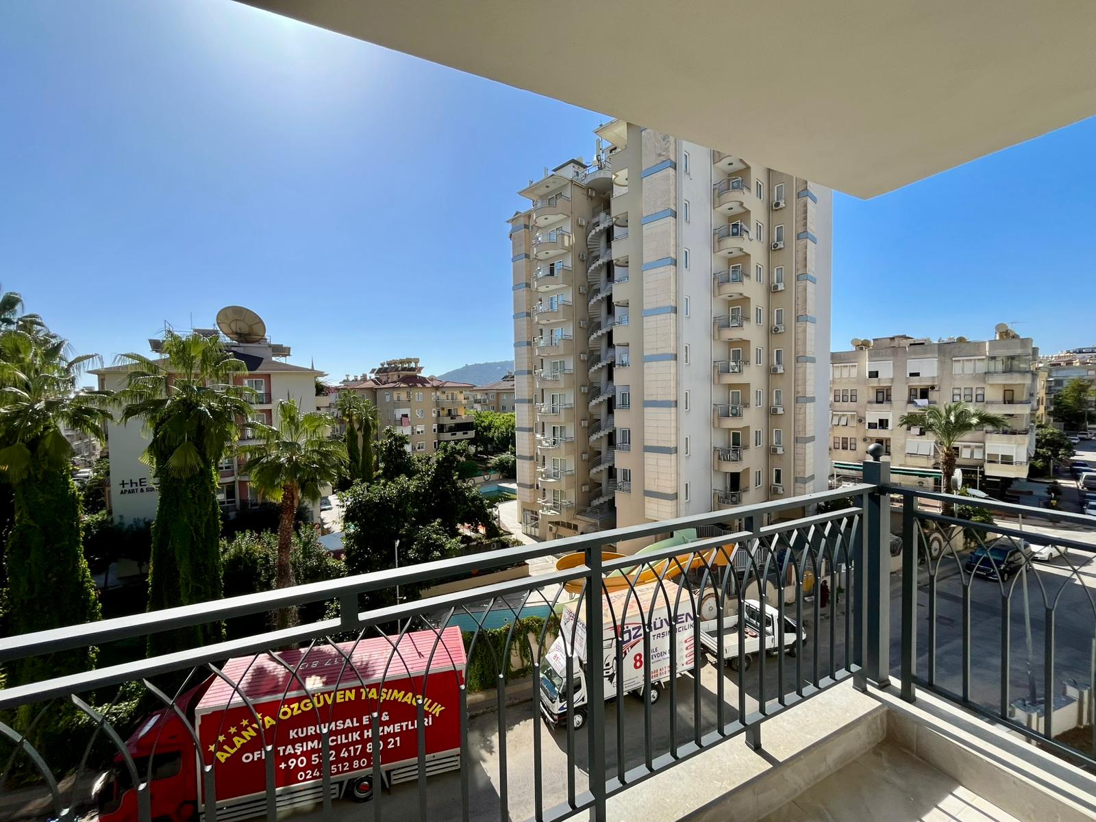 Balcony with a panoramic city-street view, palms and a mountain slope in Alanya