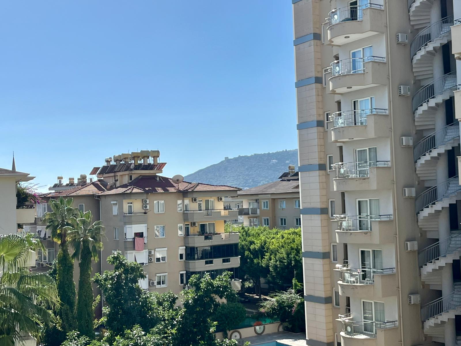 Urban buildings with palms and a mountain slope around a residence in Turkey