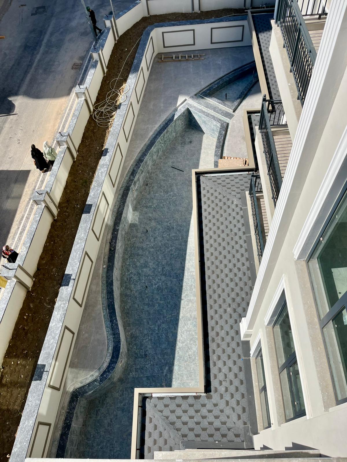 Open pool with a curved basin and gray tiling for residents of apartments in Alanya