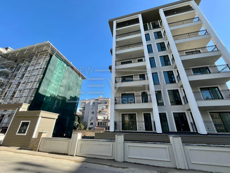 Residential building facade with open balconies and black railings for apartments for sale