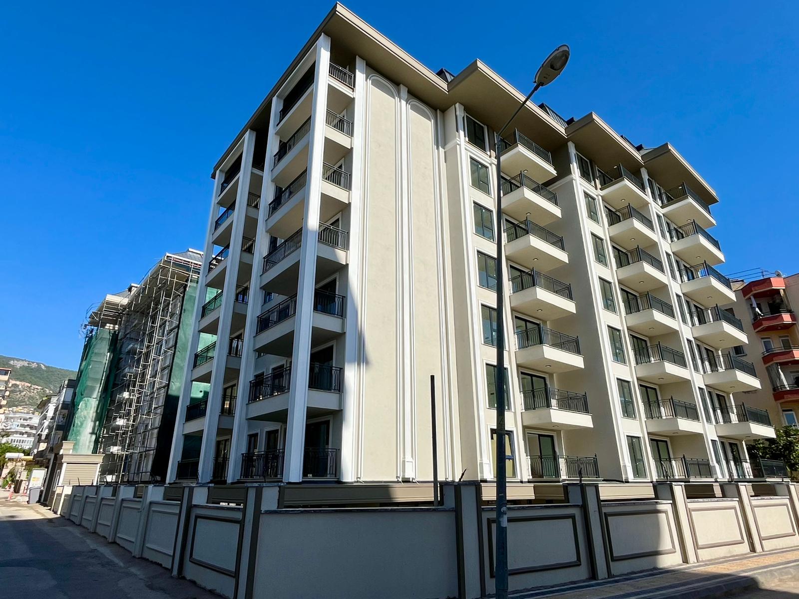 Corner facade with white decorative panels and open balconies of the Alanya property for sale