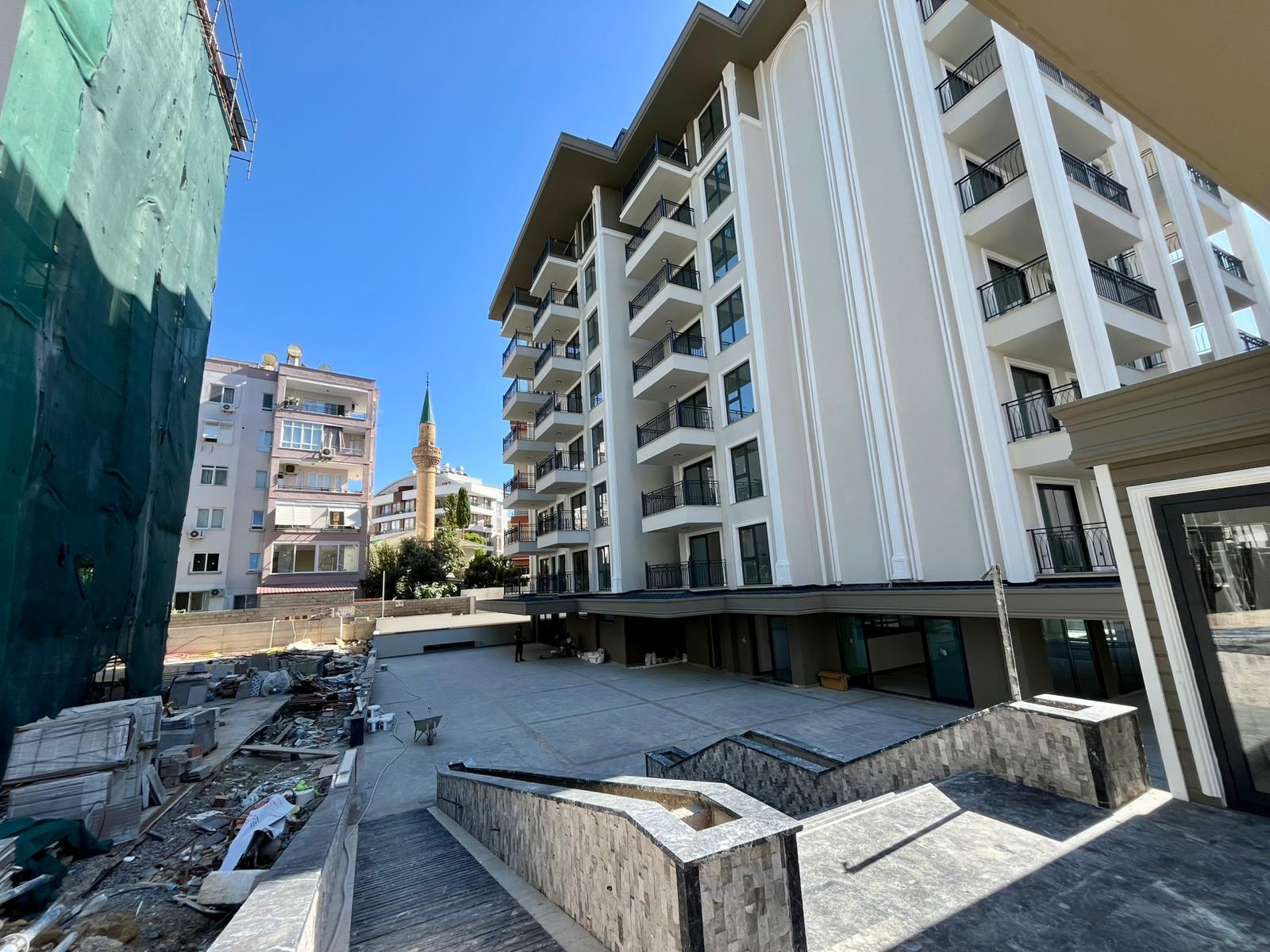 Paved courtyard with stone retaining walls and an open staircase in a complex with apartments in Alanya