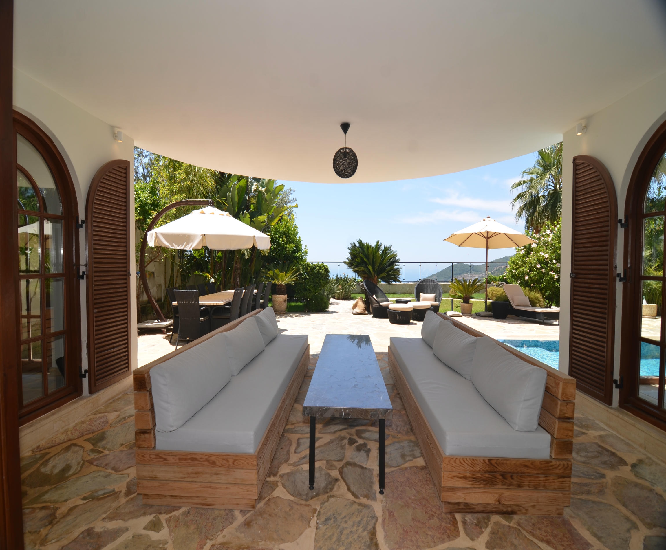 Covered terrace with white sofas and loungers overlooking the sea at a villa for sale in Turkey