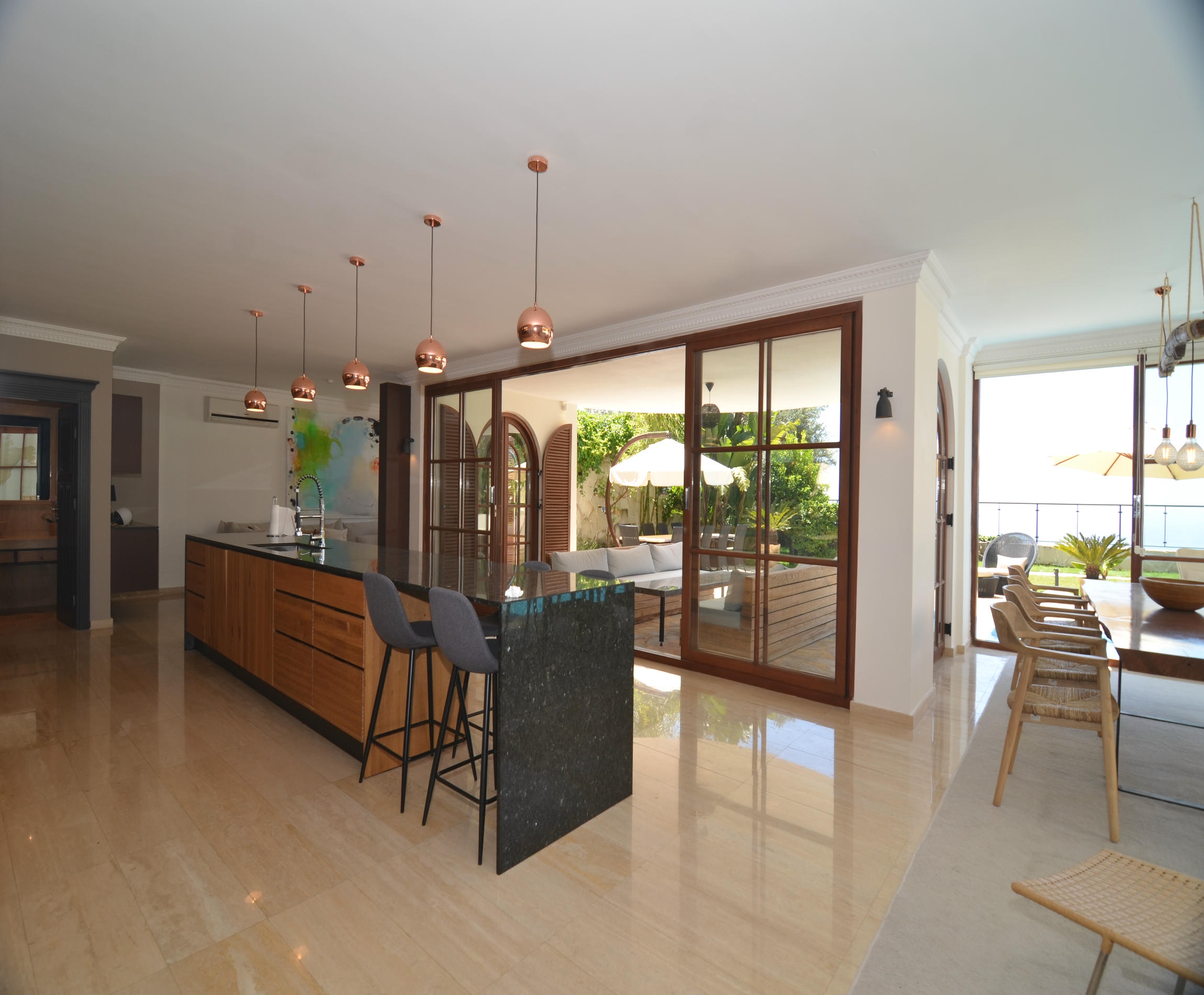 Kitchen with a dark stone island and copper pendant lights overlooking the terrace and sea at an Alanya villa