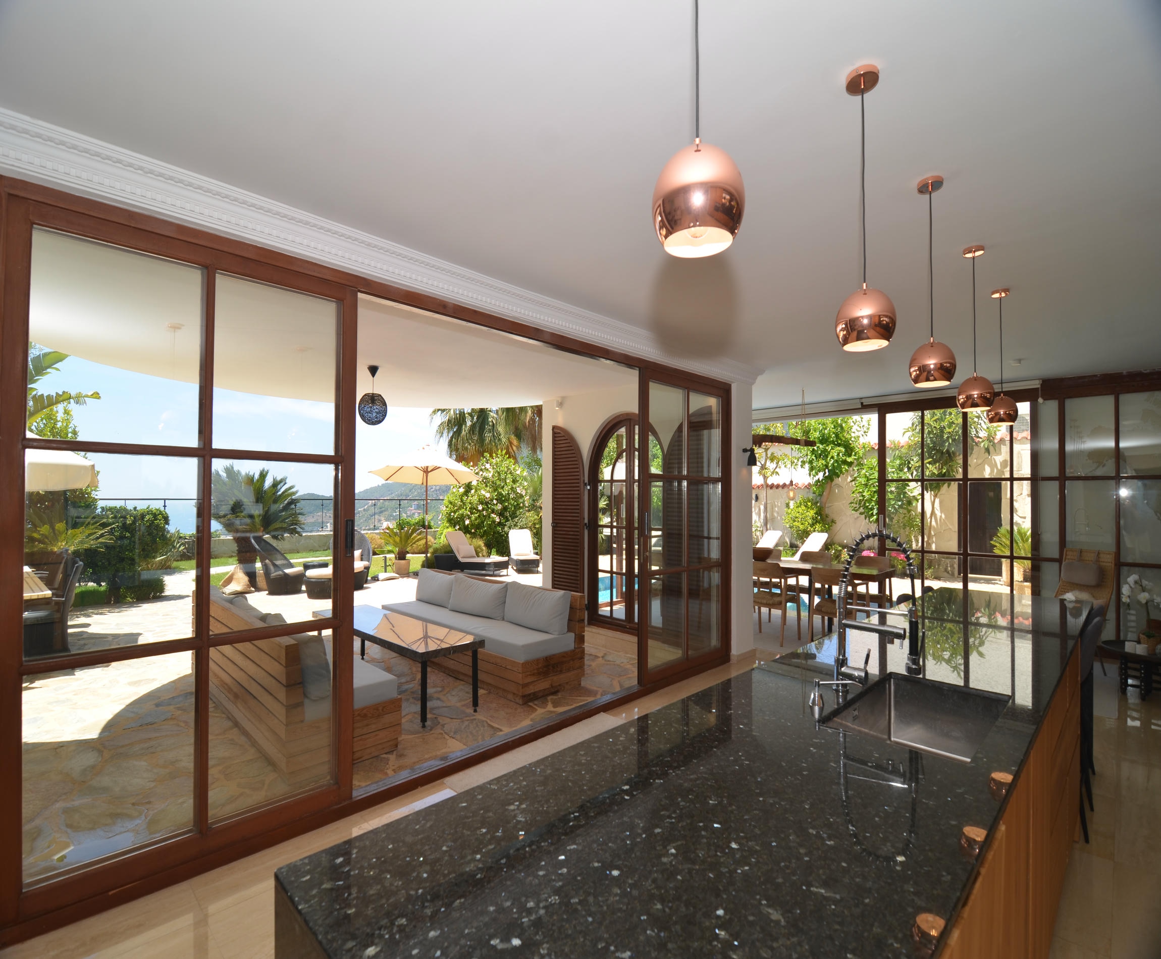 Kitchen with a wooden island and panoramic glazing opening toward the sea in Alanya