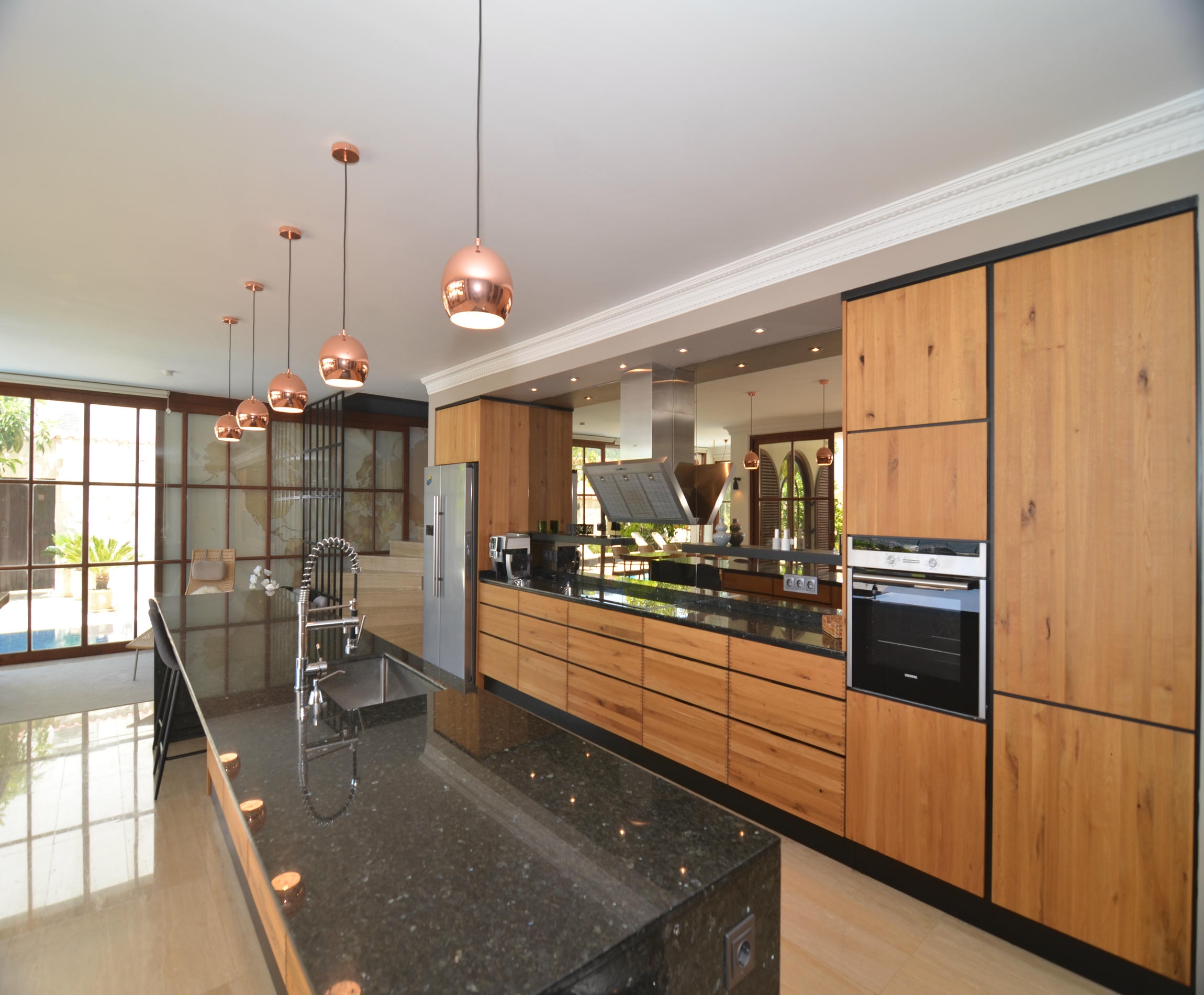 Kitchen with tall wooden cabinets and a black stone worktop in an Alanya house