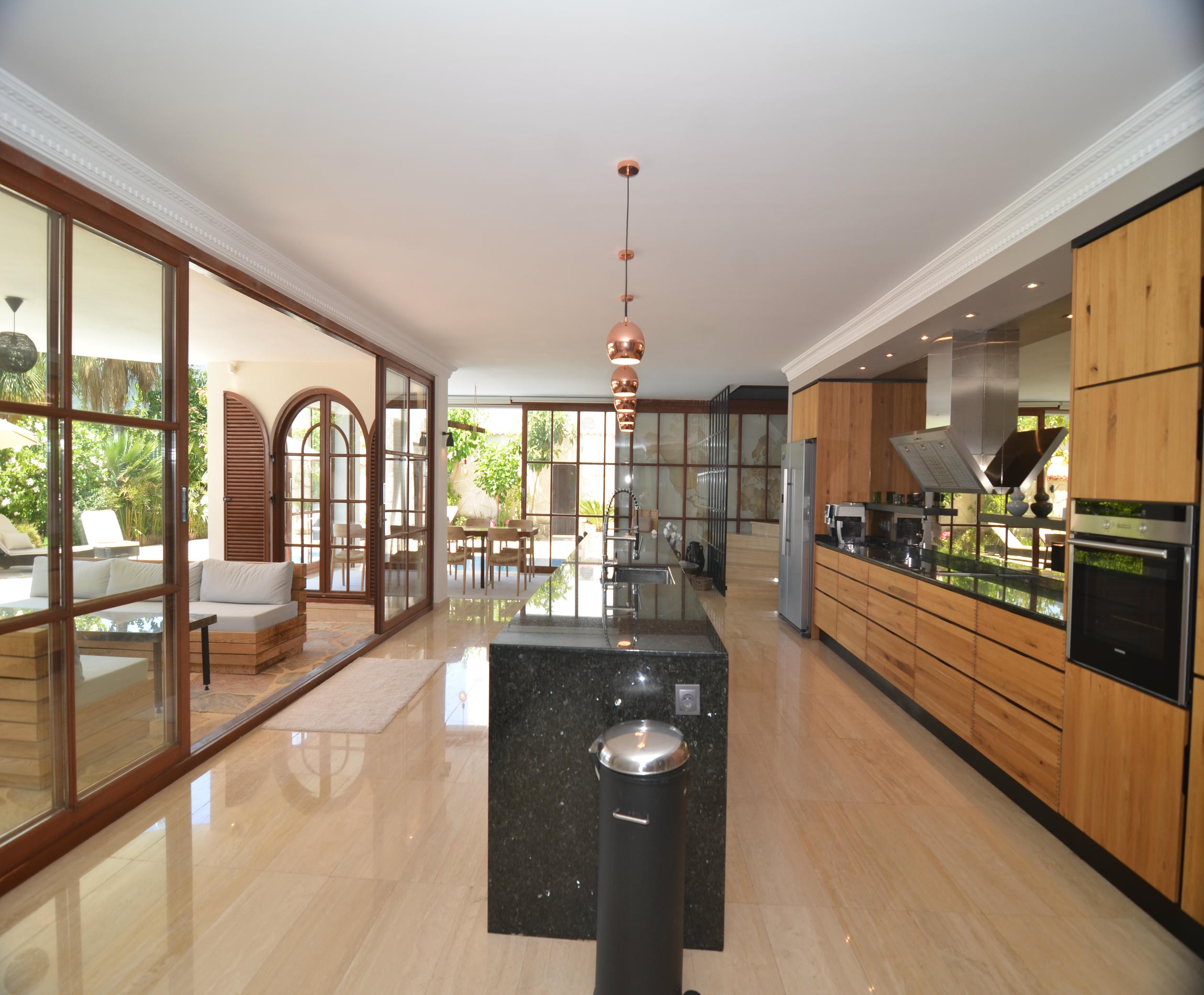 Open-plan kitchen living room with a black stone island and panoramic glazing in a villa