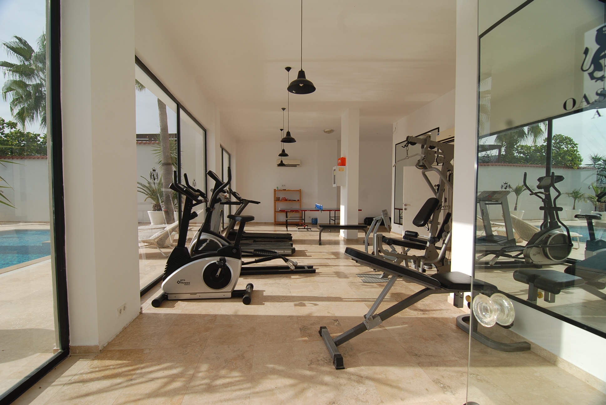 Gym with a treadmill, exercise bike and mirrored wall beside panoramic windows