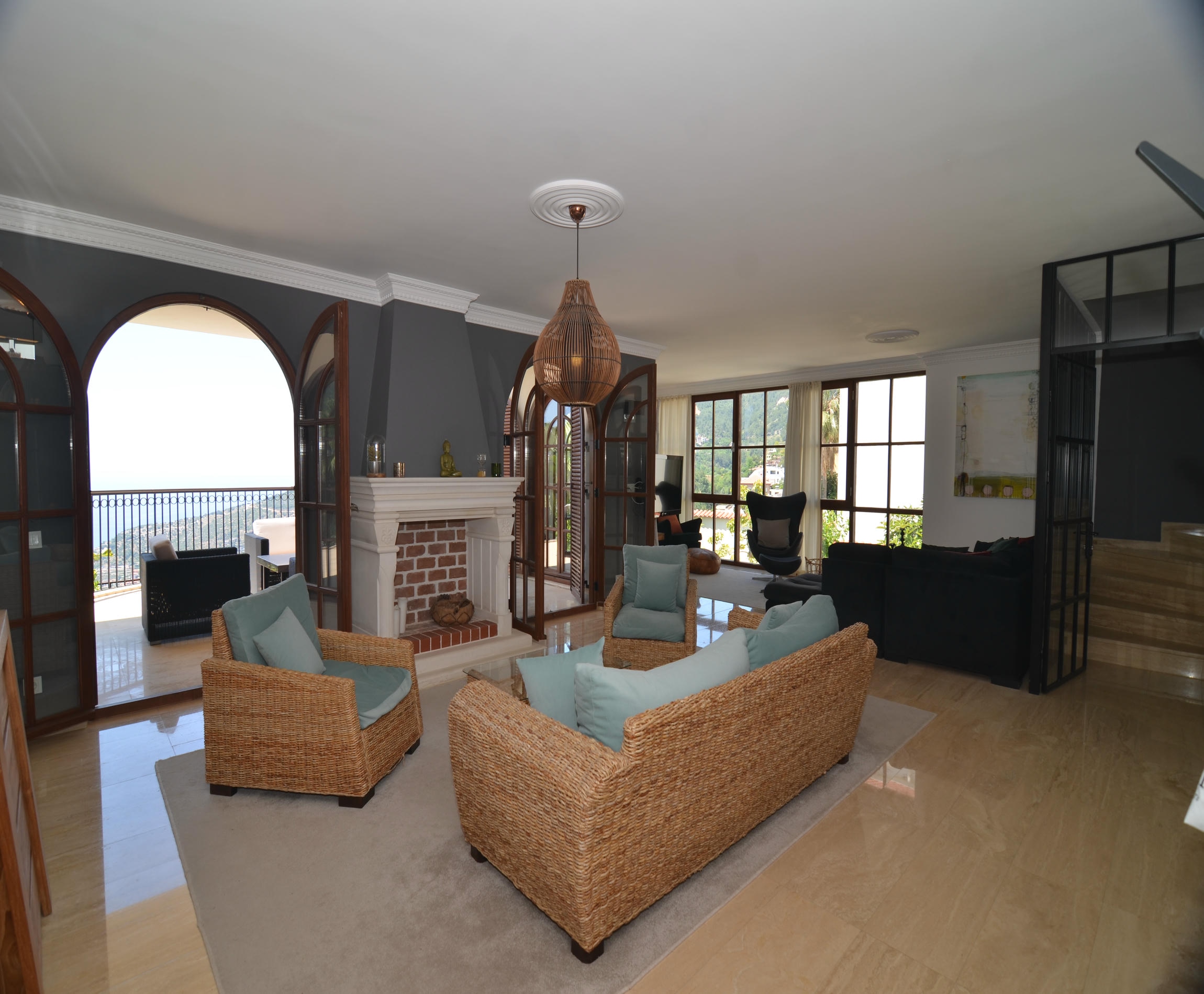 Living room with wicker seating and a brick fireplace overlooking the sea in Alanya, Turkey