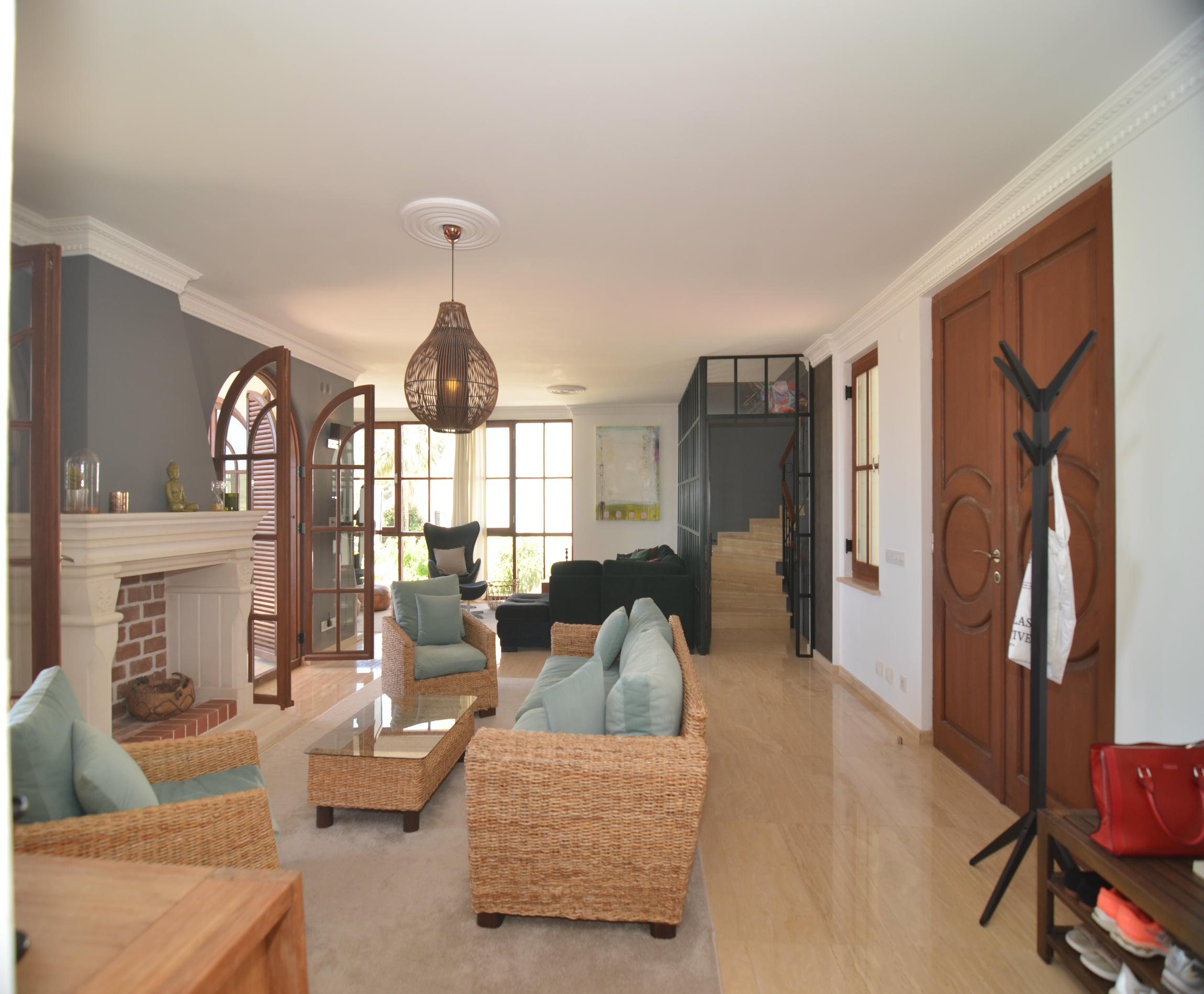 Living room with a fireplace, wicker chairs and black glass partition in a house for sale in Turkey