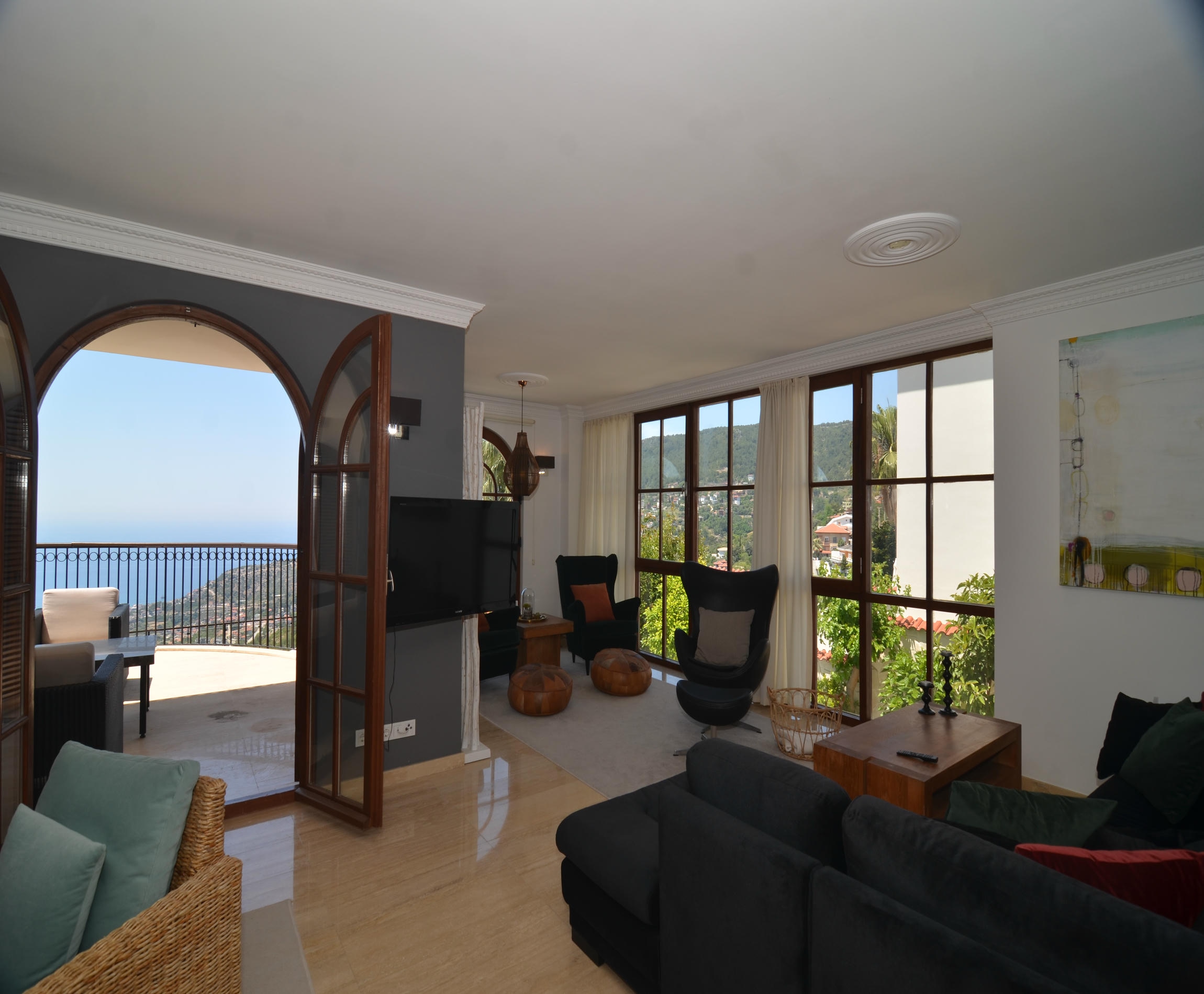 Living room with a dark sofa and floor-to-ceiling windows overlooking the sea in an Alanya villa, Turkey
