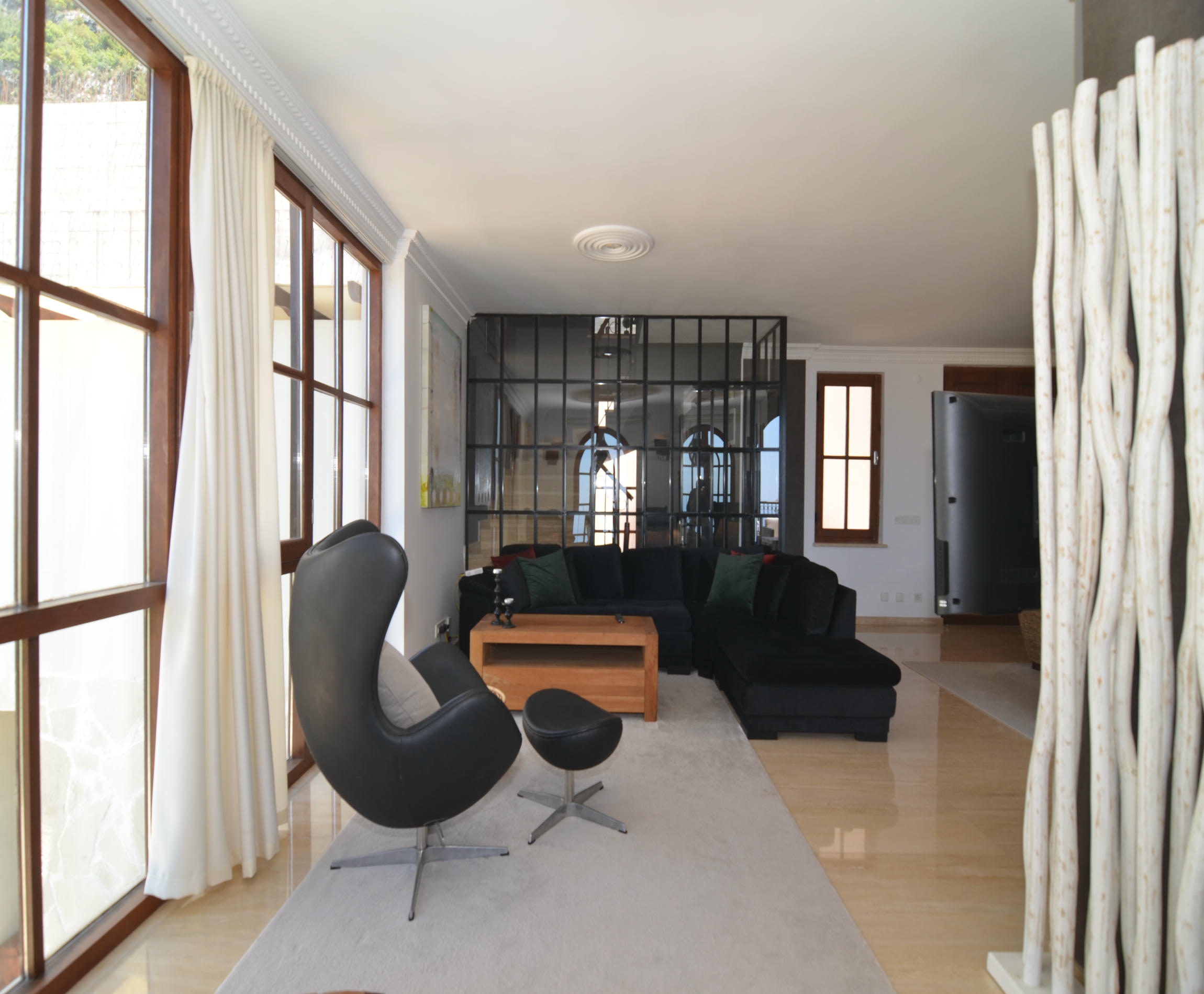 Living room with a corner sofa, black chair and branch partition in an Alanya villa in Turkey