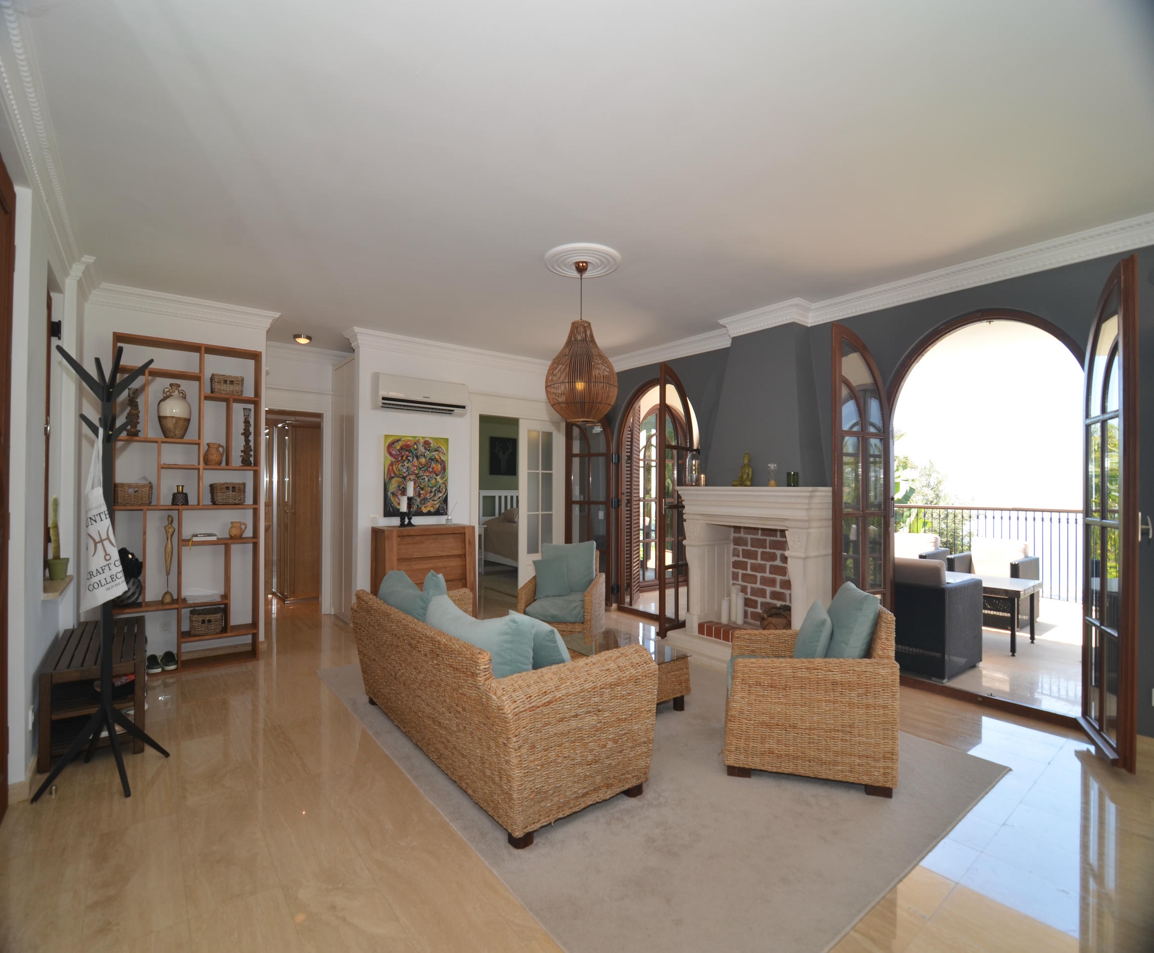 Living room with wicker furniture, brick fireplace and arched windows