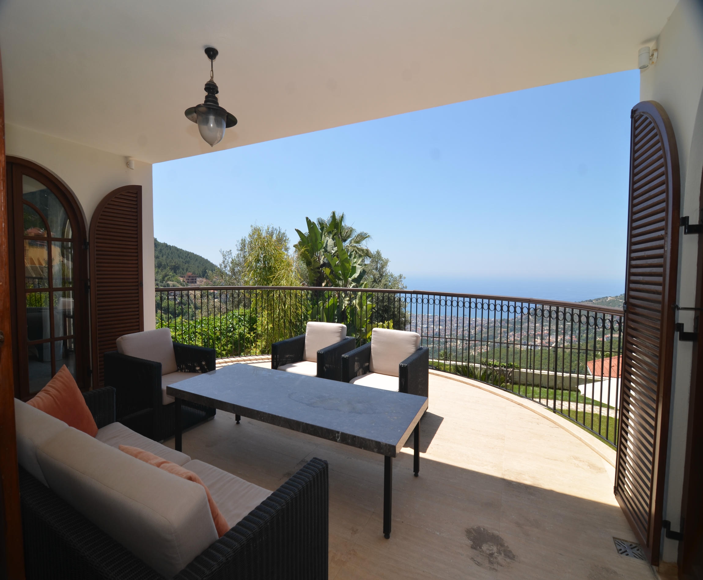 Terrace with outdoor dining furniture and decorative metal railing overlooking the sea at a villa for sale in Turkey