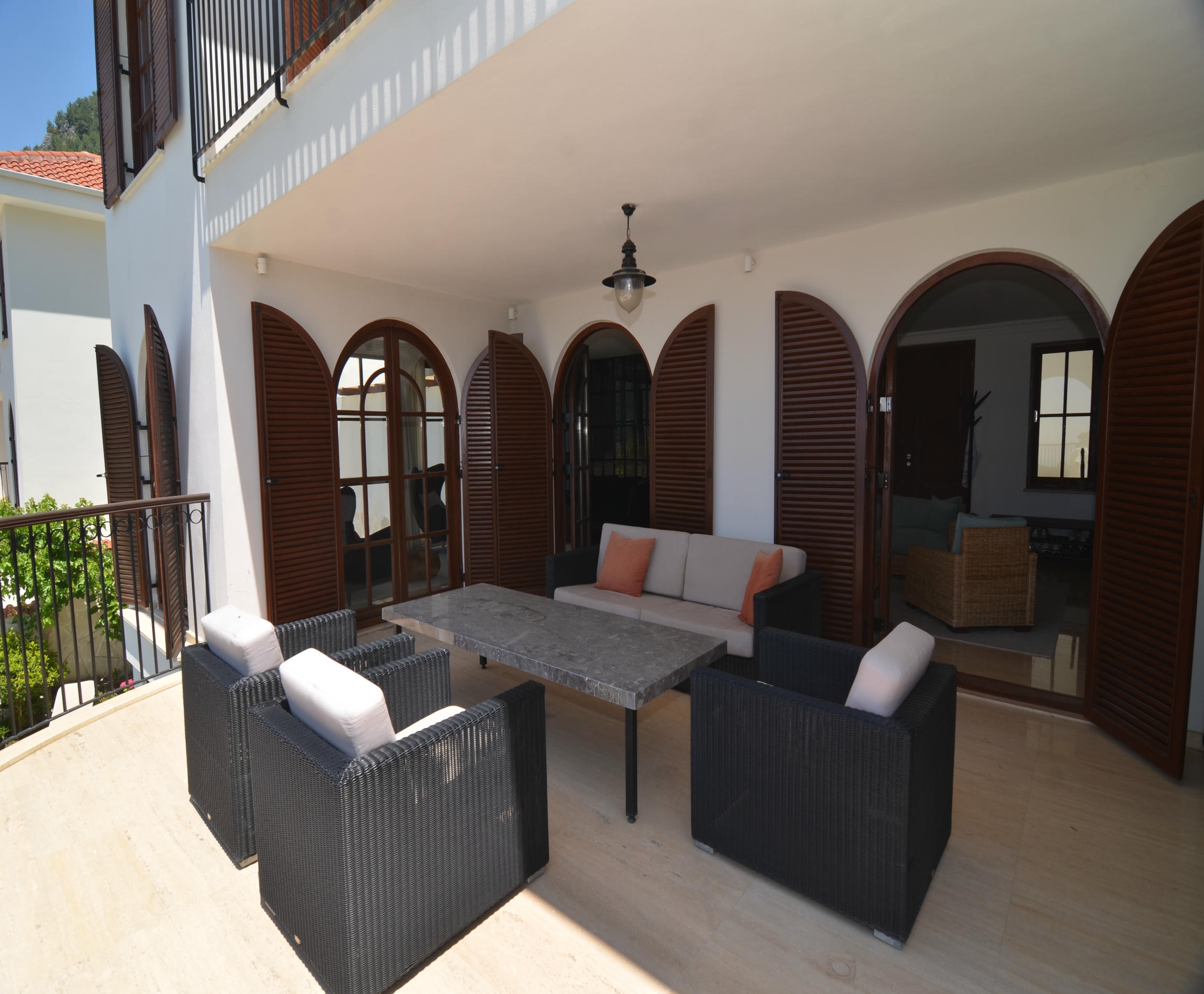 Terrace with wicker chairs and arched doors overlooking greenery in Alanya, Turkey