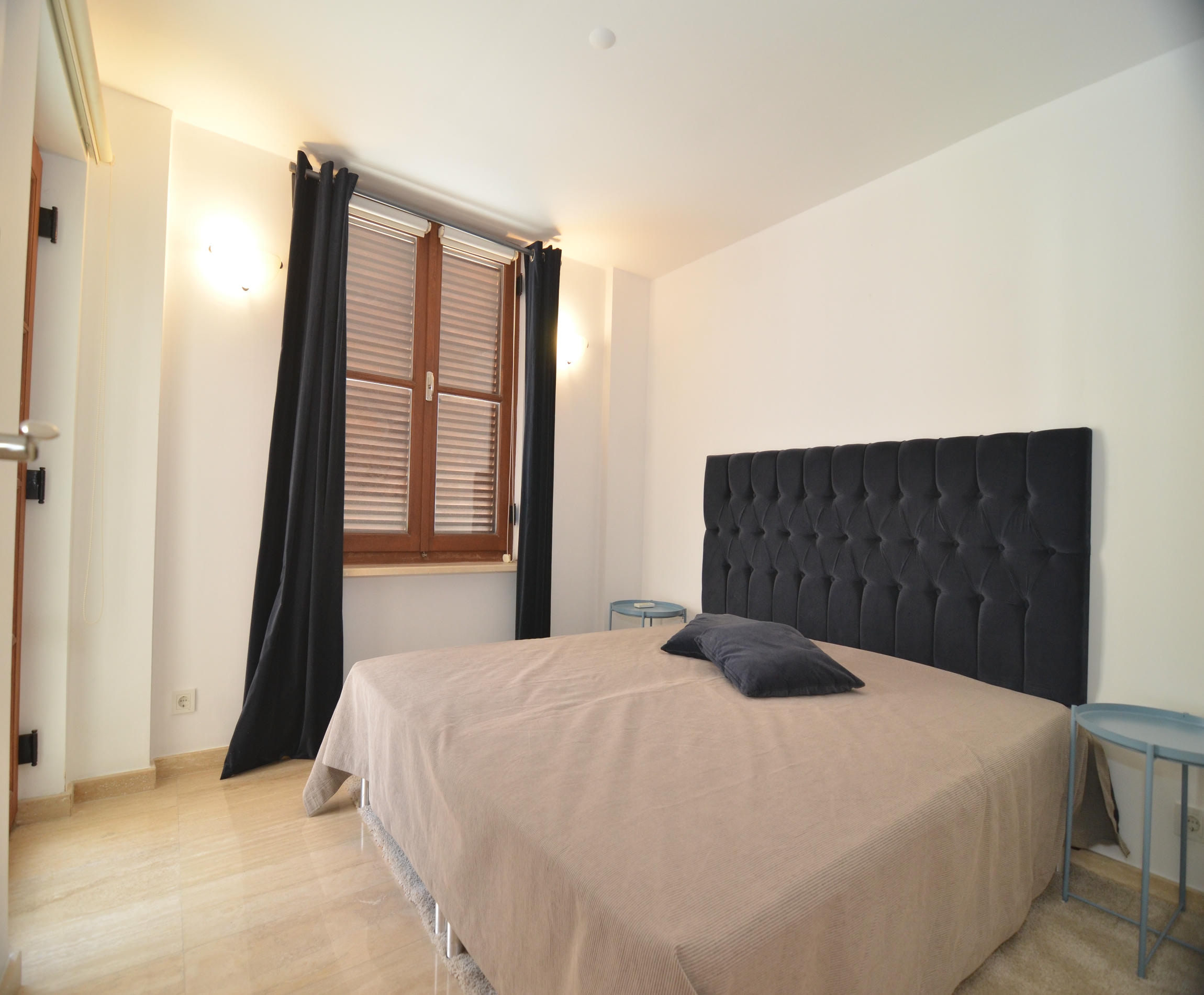 Bedroom with a double bed, black headboard and dark curtains in a villa