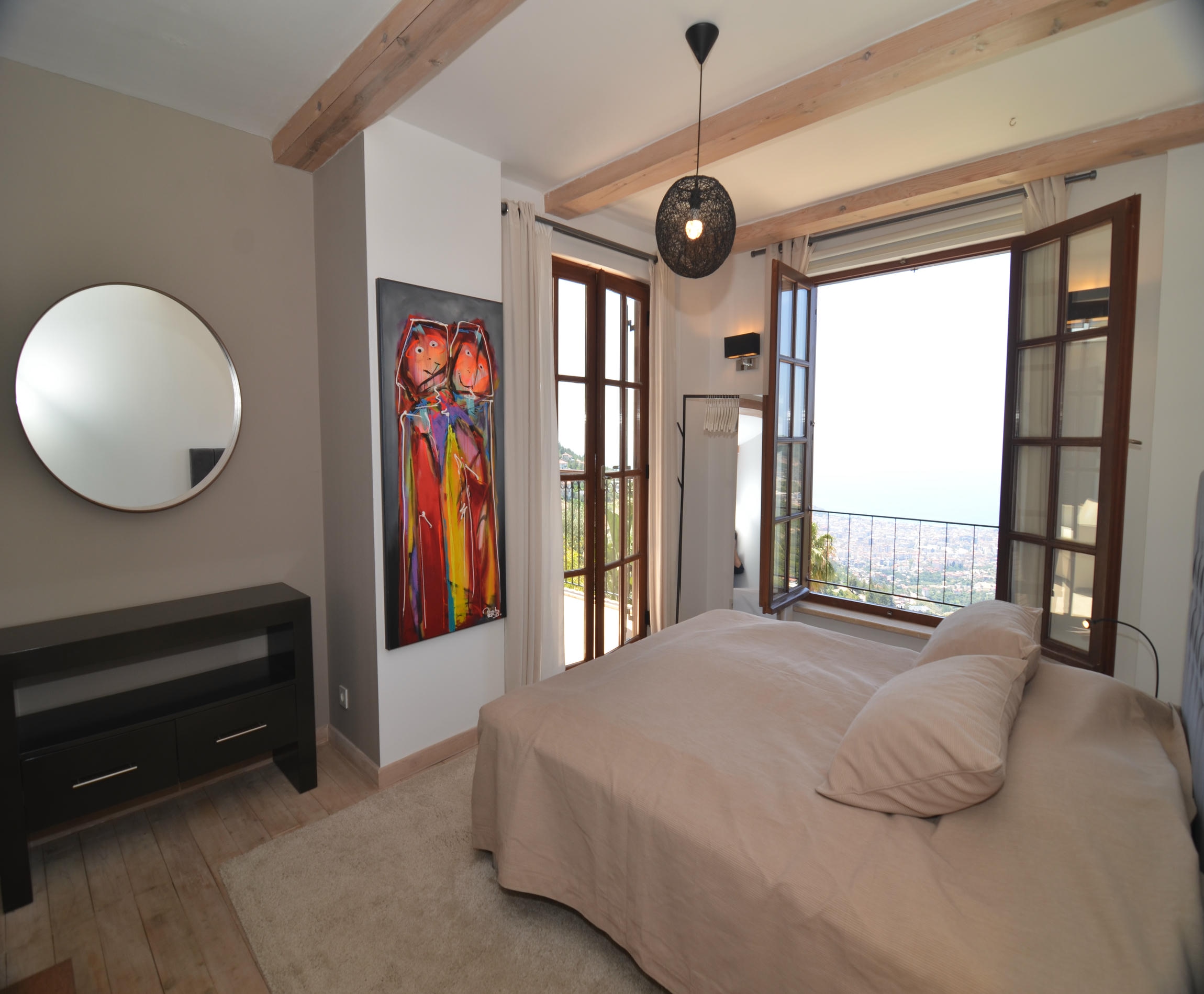 Bedroom with a beige bed and panoramic windows overlooking the city in an Alanya villa