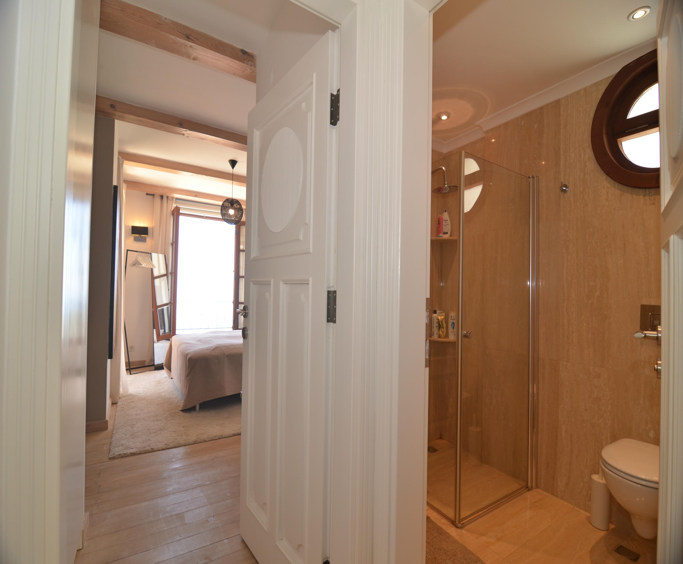 Bathroom with a glass shower cabin, vessel sink and round window