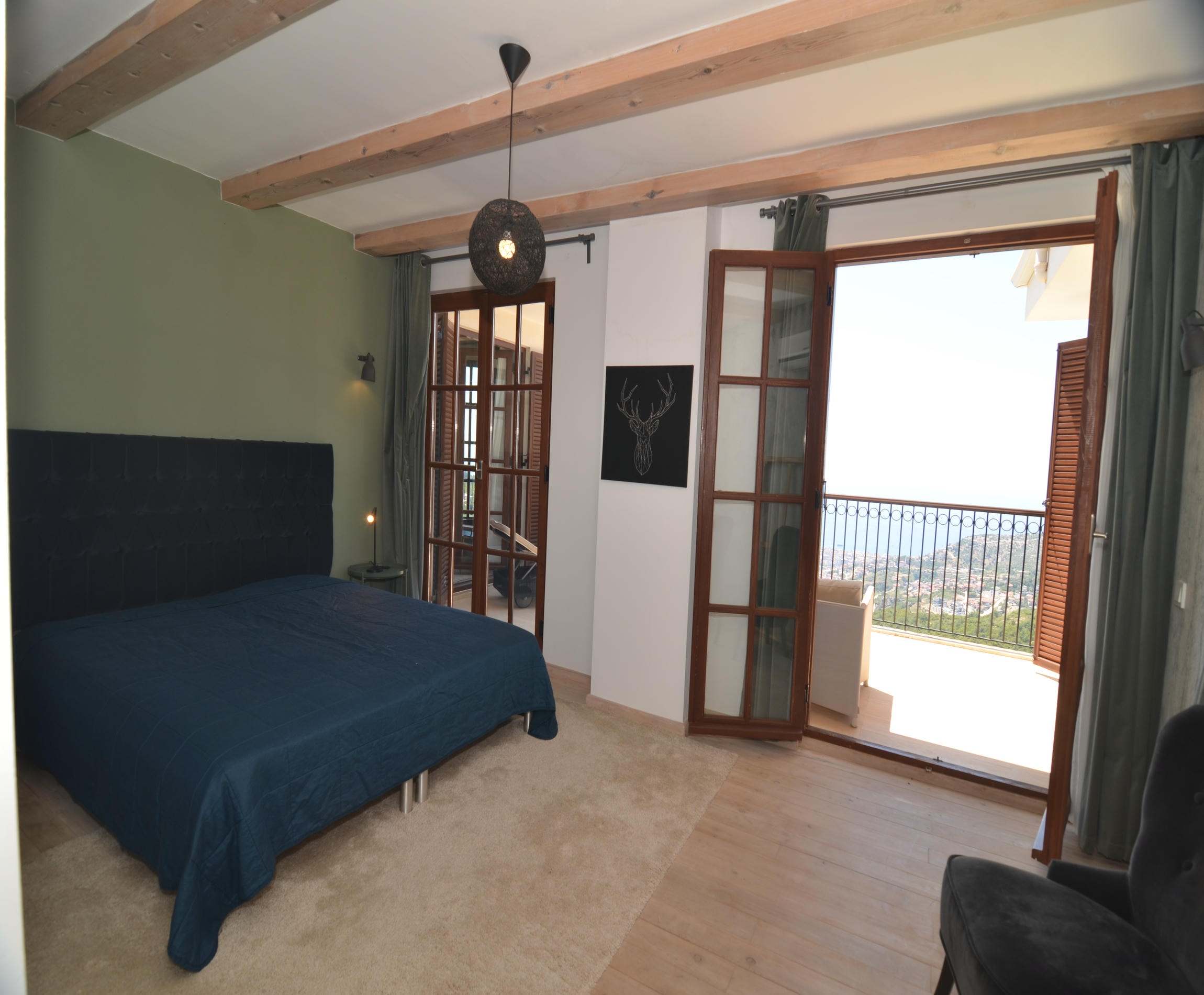 Bedroom with a dark blue bed and balcony door in a villa