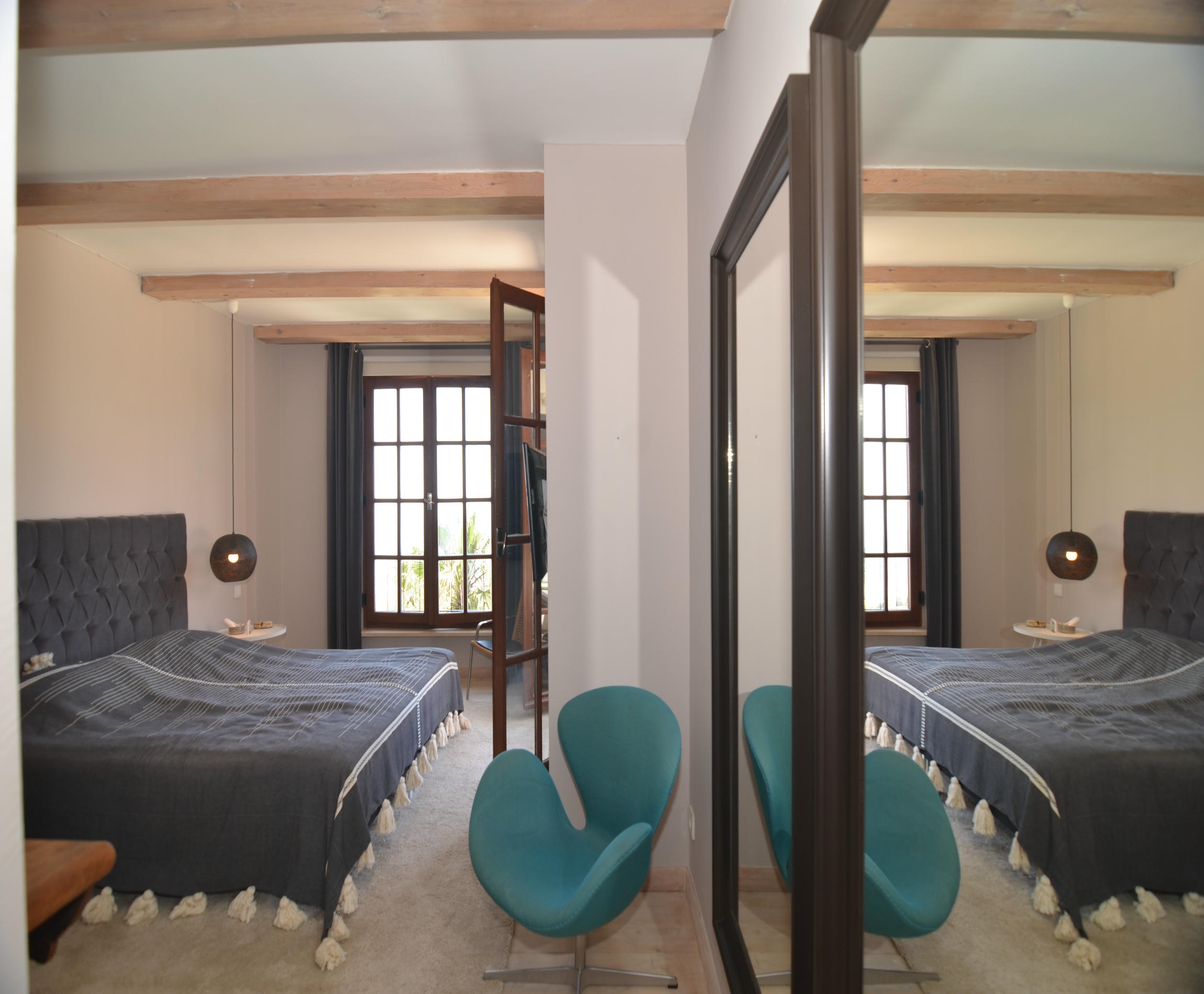Bedroom with a gray bed, mirrored wardrobe door and timber beams in Alanya