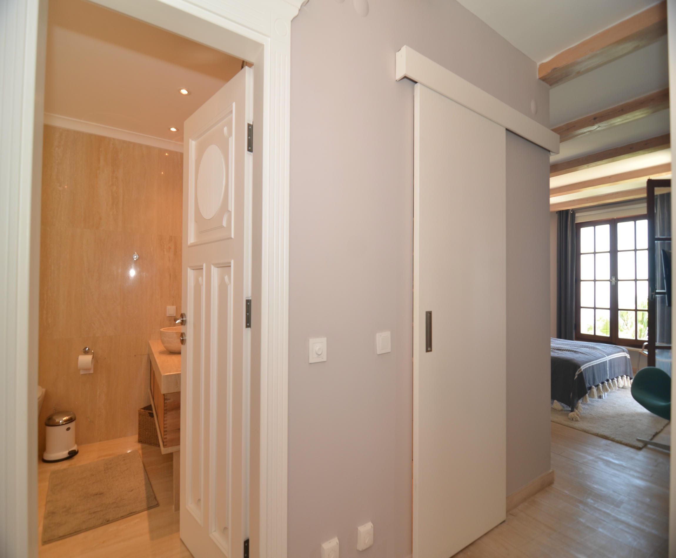 Hallway with wooden flooring, bathroom door and view toward the bedroom