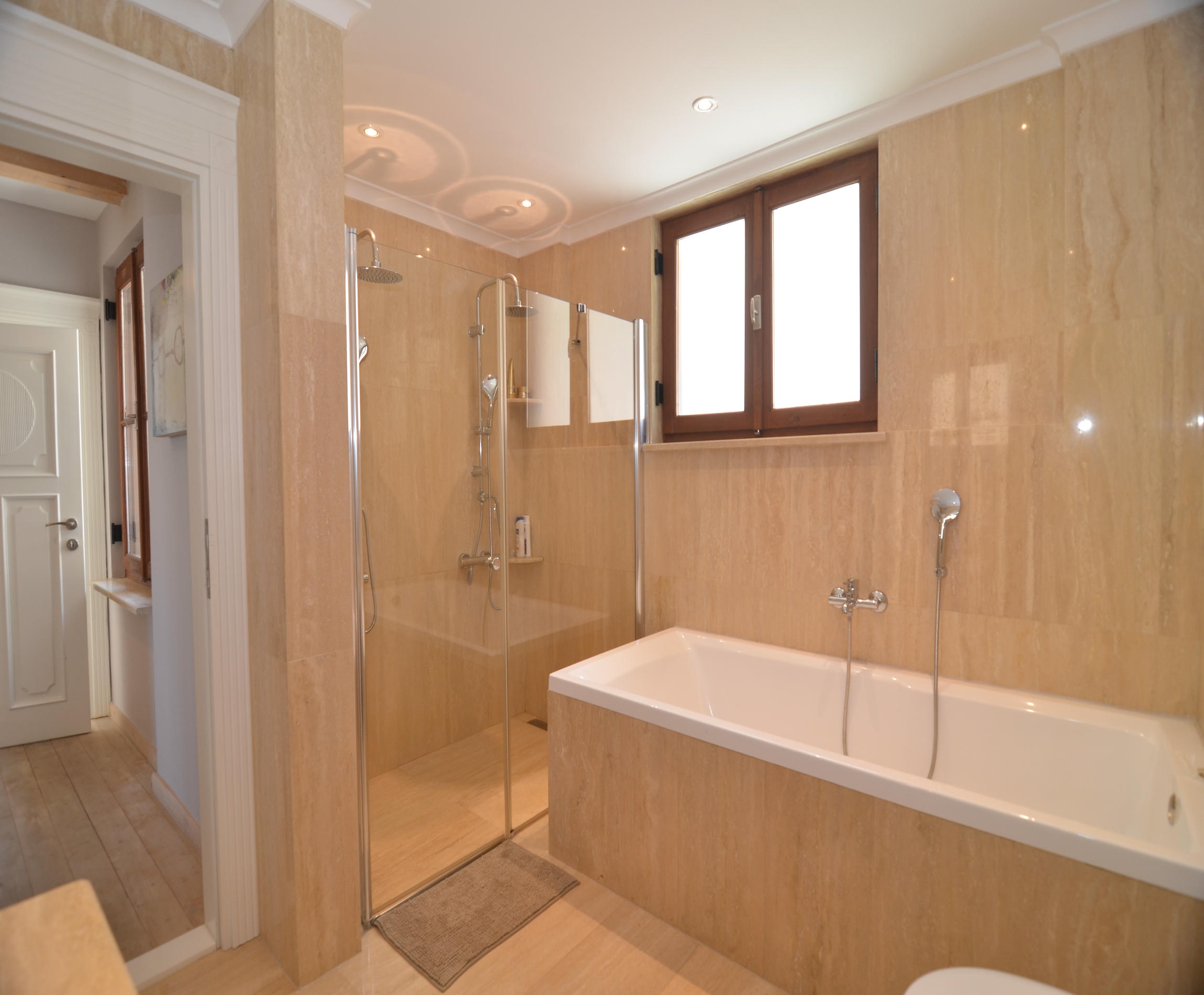 Bathroom with a white bathtub and glass shower cabin in an Alanya house