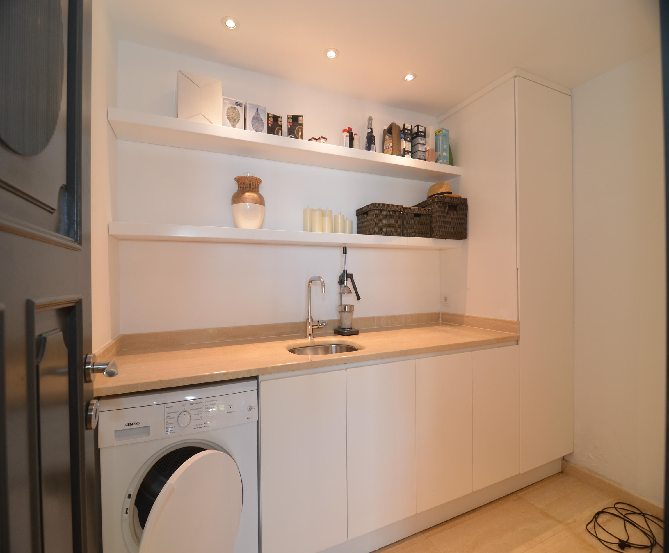 Laundry room with a front-loading washing machine and worktop in a villa