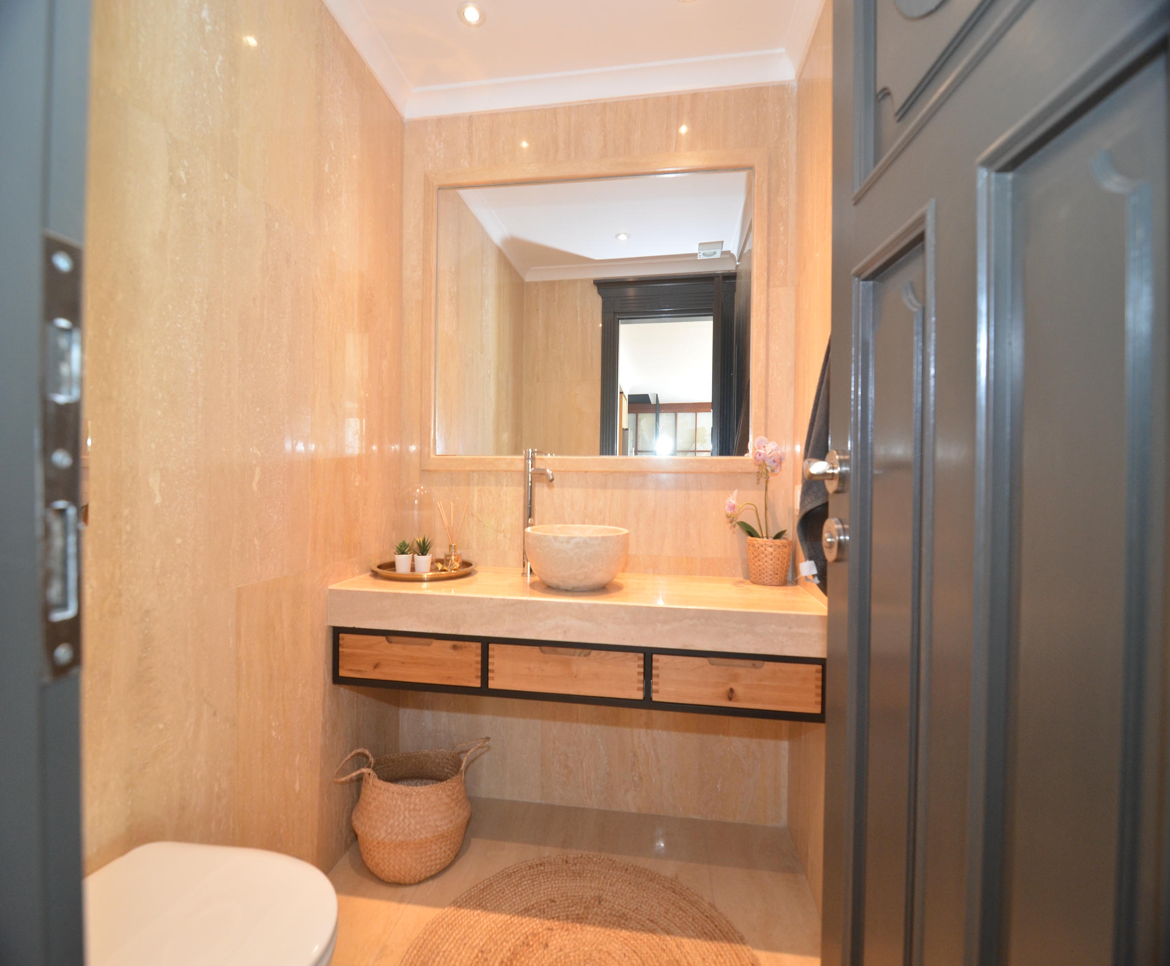 Bathroom with a vessel sink, wooden vanity and beige wall and floor finishes
