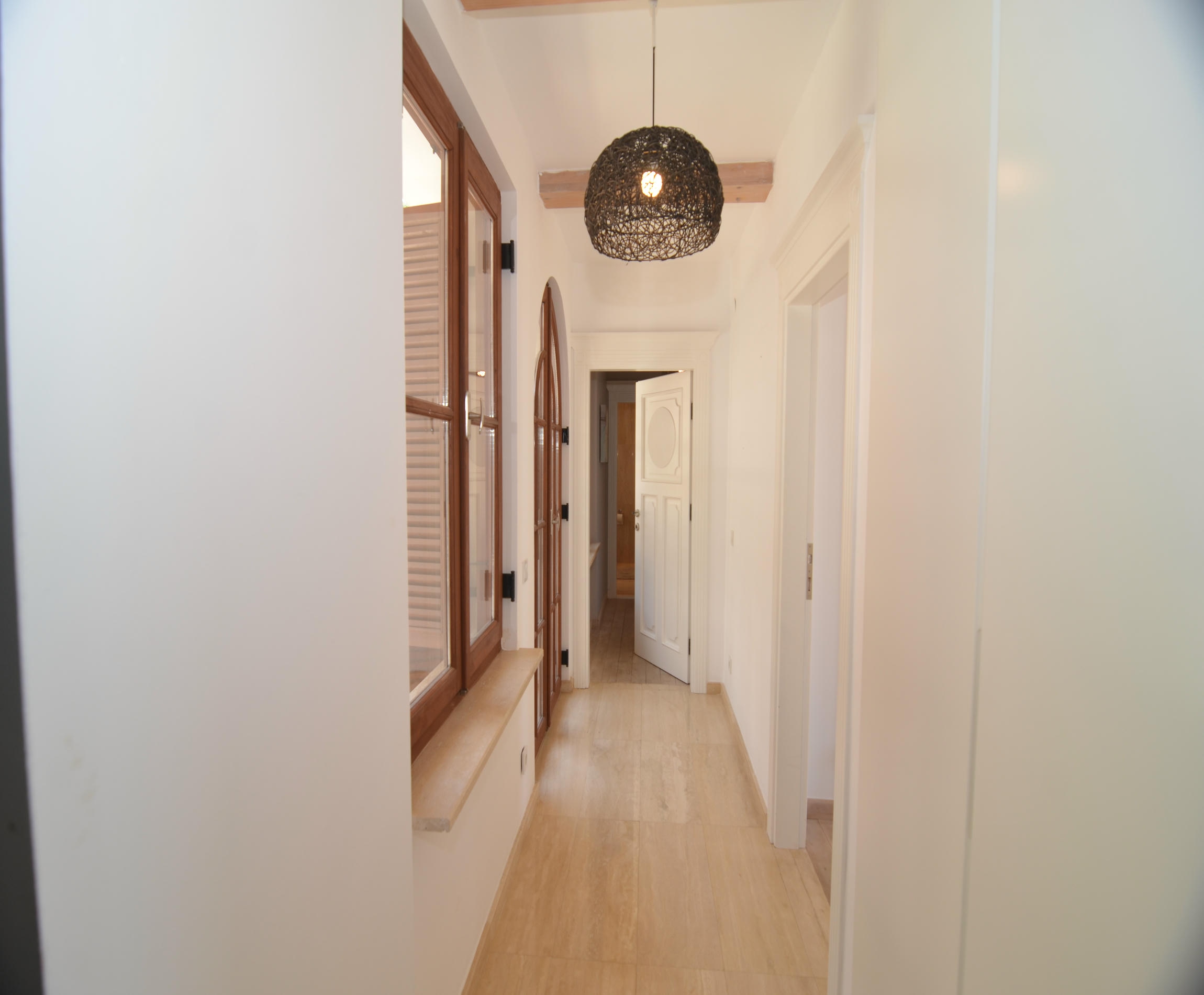 Bright hallway with panoramic window, wooden floor and white doors in a villa