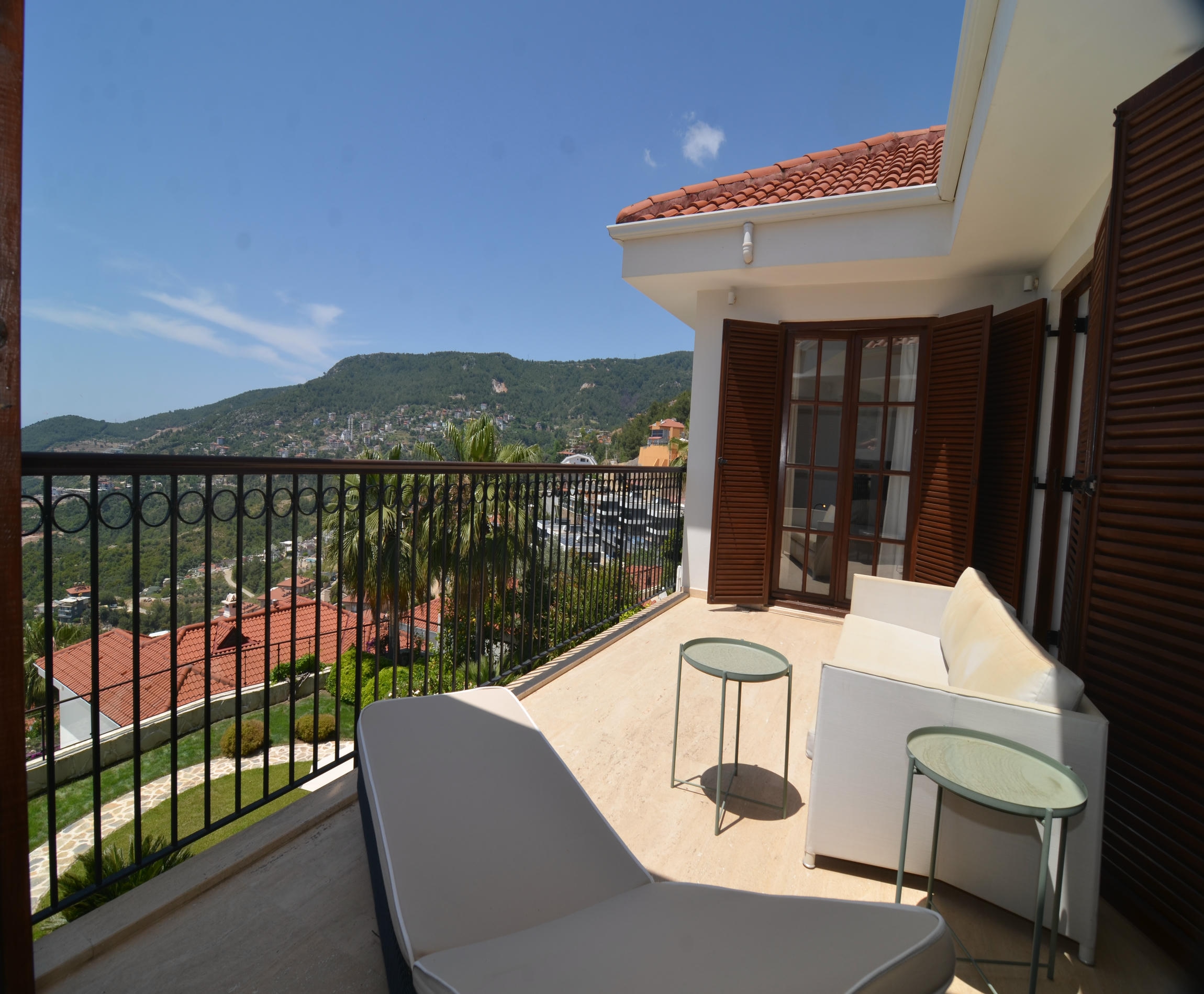 A terrace of a house for sale in Turkey with a white outdoor sofa and mountain slope view