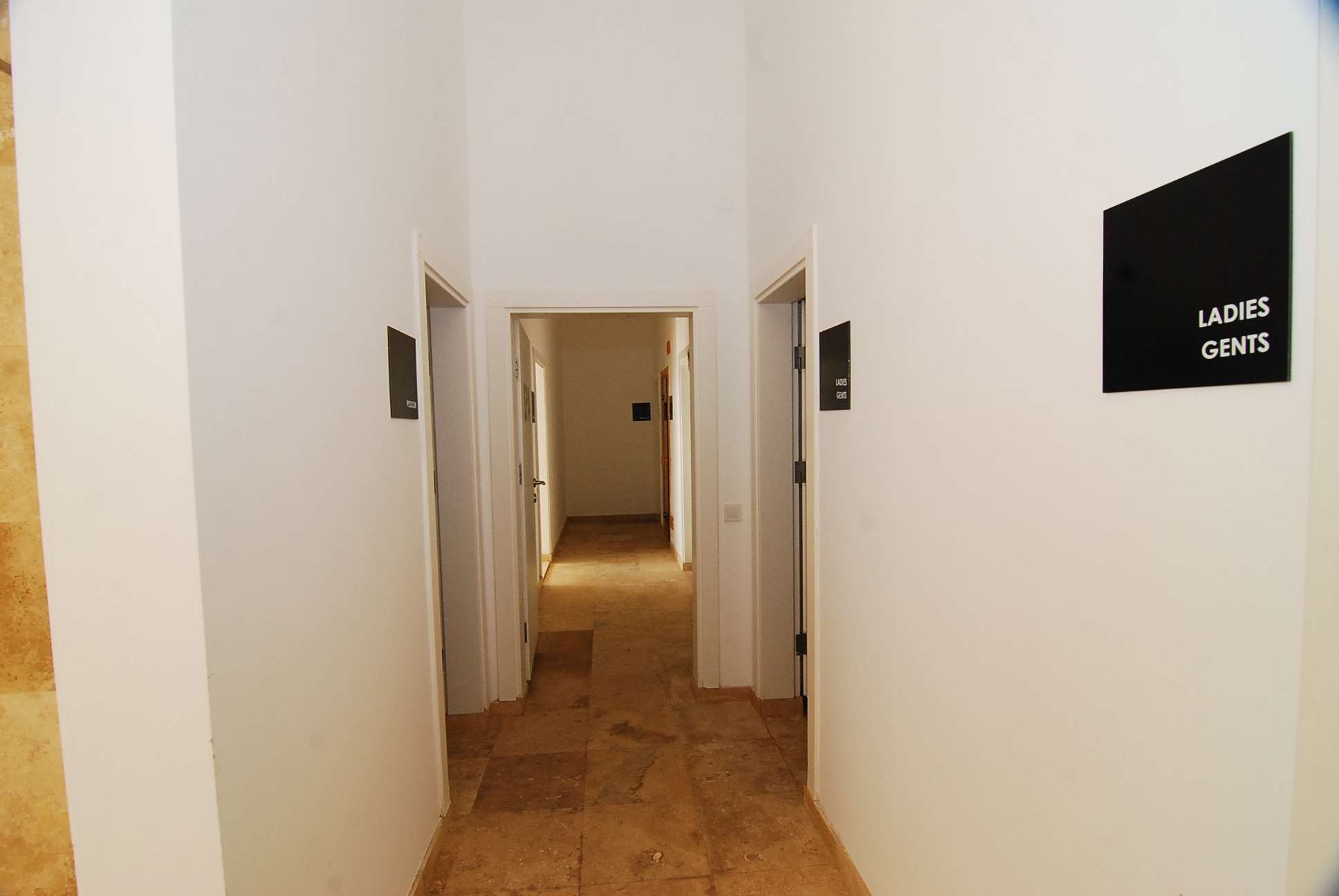 Hallway with doors on both sides, stone flooring and warm ceiling lighting