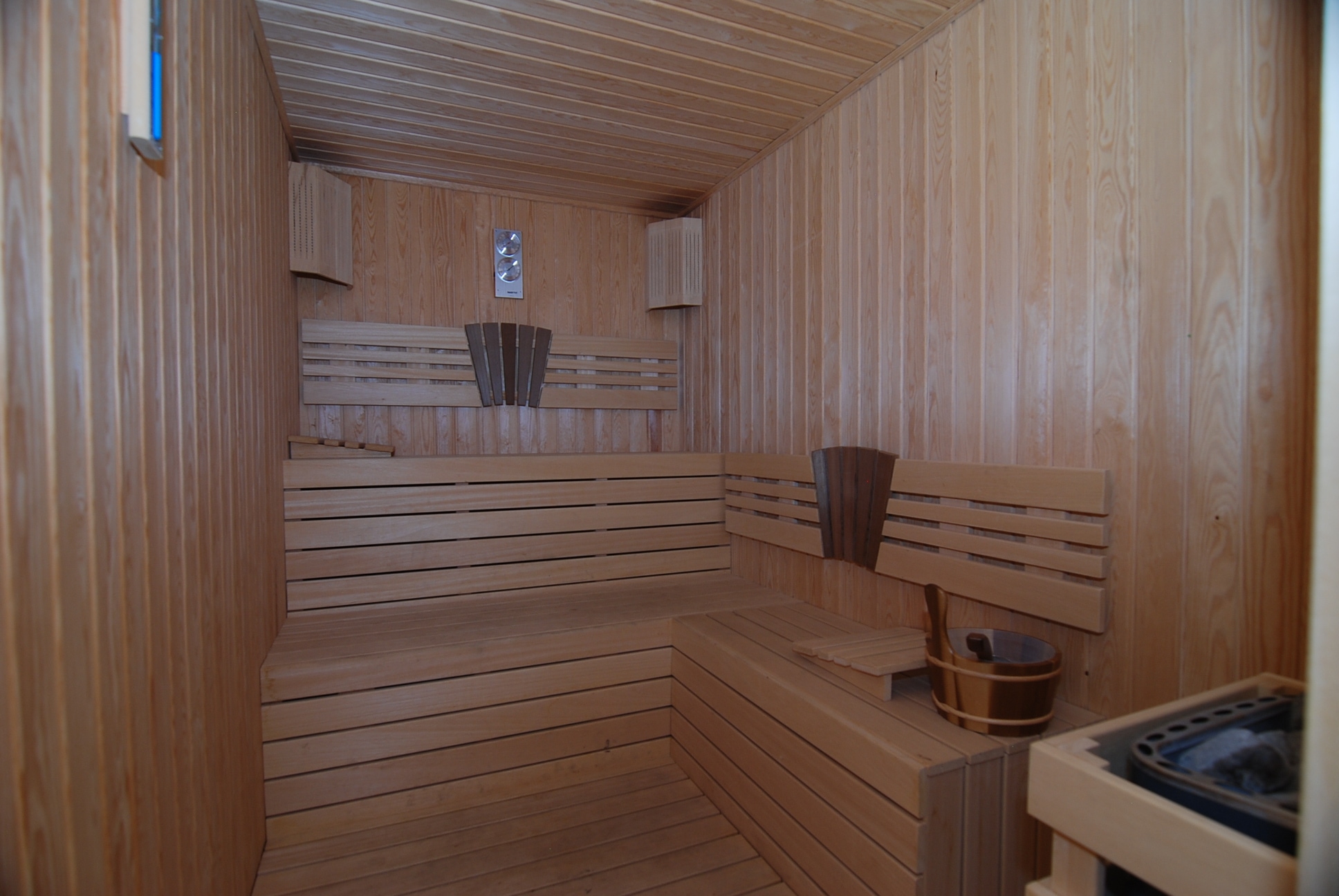 Sauna with tiered wooden benches and an electric heater for residents of detached homes
