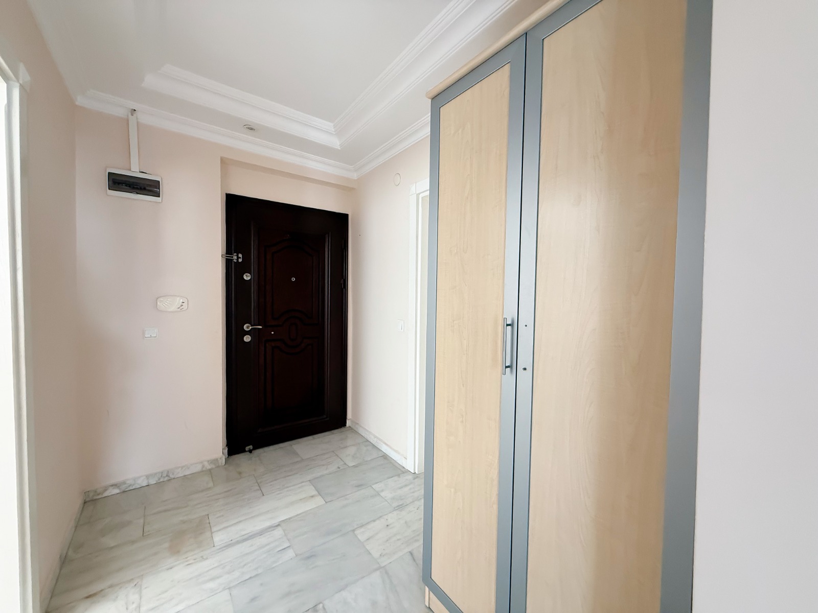 Walk-in wardrobe with a tall built-in closet and black entry door in an apartment in Mahmutlar