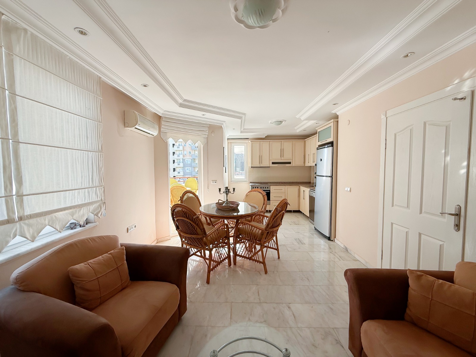 Brown sofas and a corner kitchen with a tall silver refrigerator in Turkey