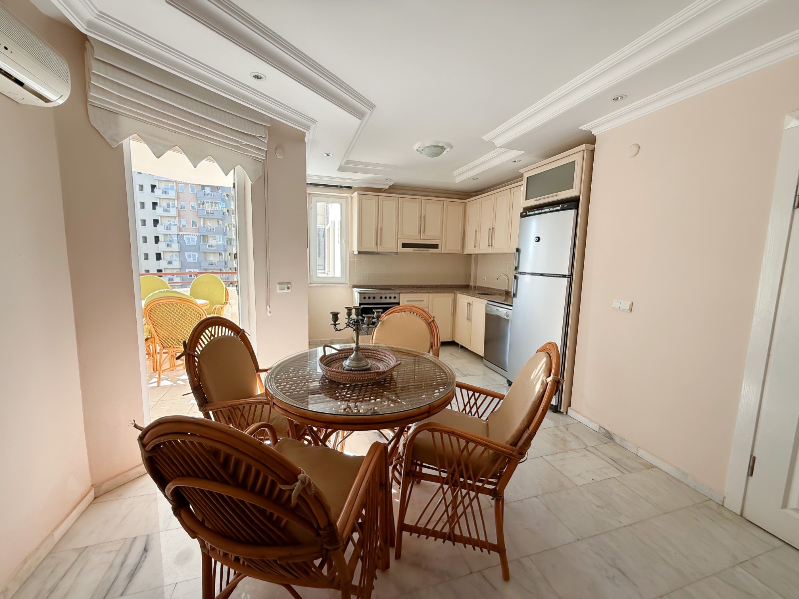 Kitchen-living room with a round table and neighboring buildings in a 2+1 apartment for sale in Mahmutlar