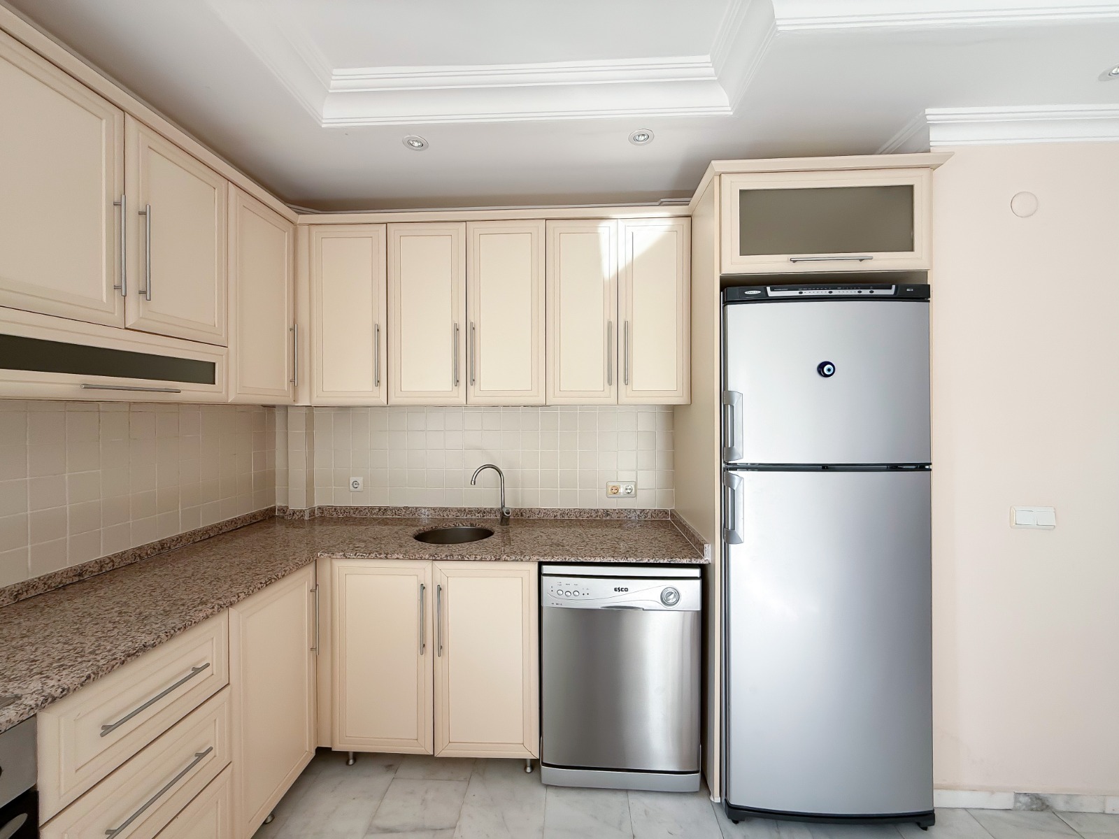 Granite-worktop kitchen with a dishwasher and cream cabinets in Mahmutlar
