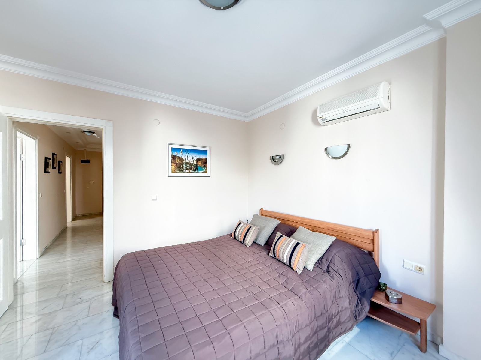 A wooden headboard and brown quilt define the bedroom in a residence