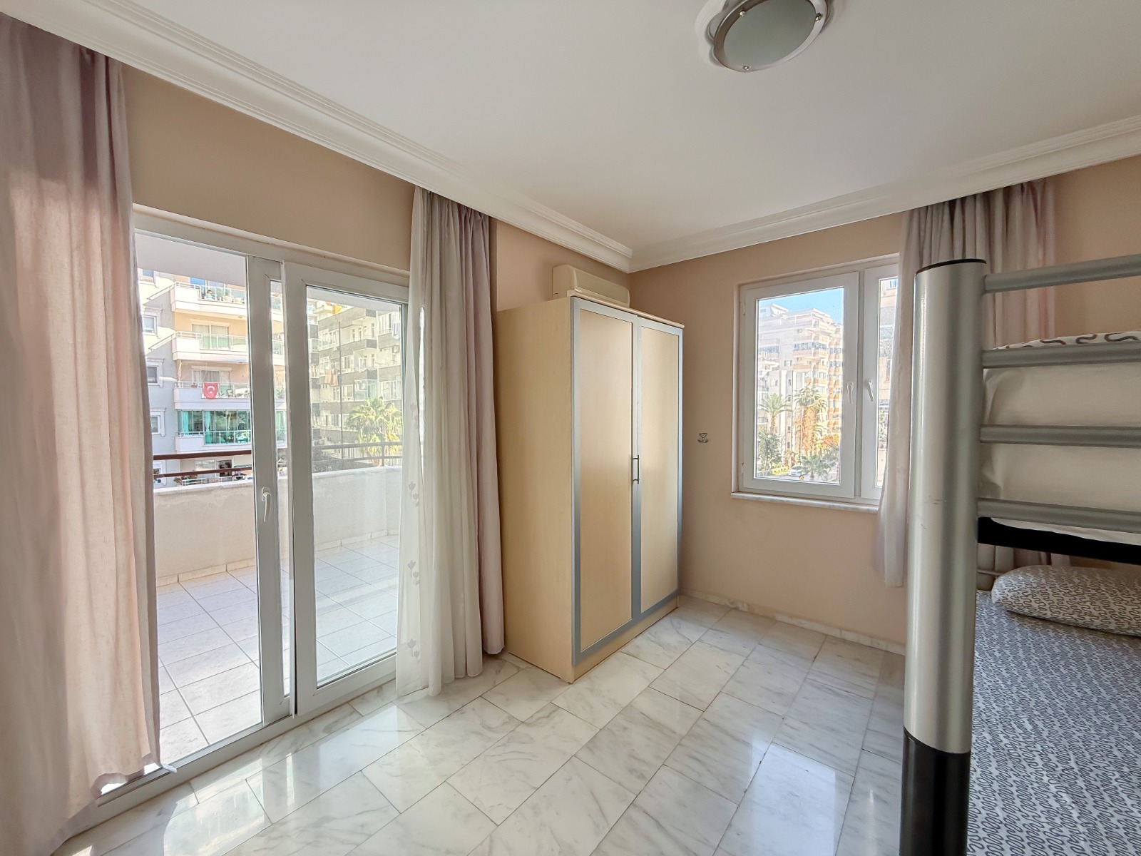 Bedroom with a bunk bed, built-in closet and panoramic balcony door overlooking the city