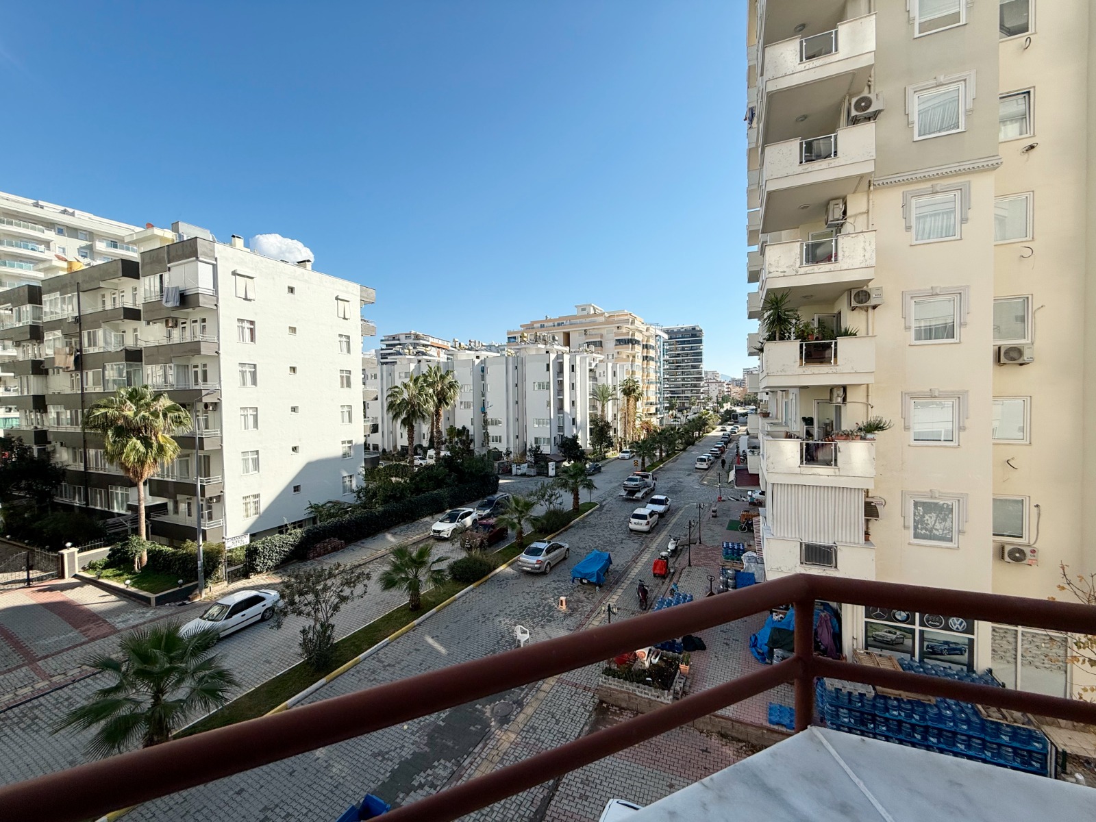 Balcony view of a city street with palms and parked cars in Turkey where property is for sale