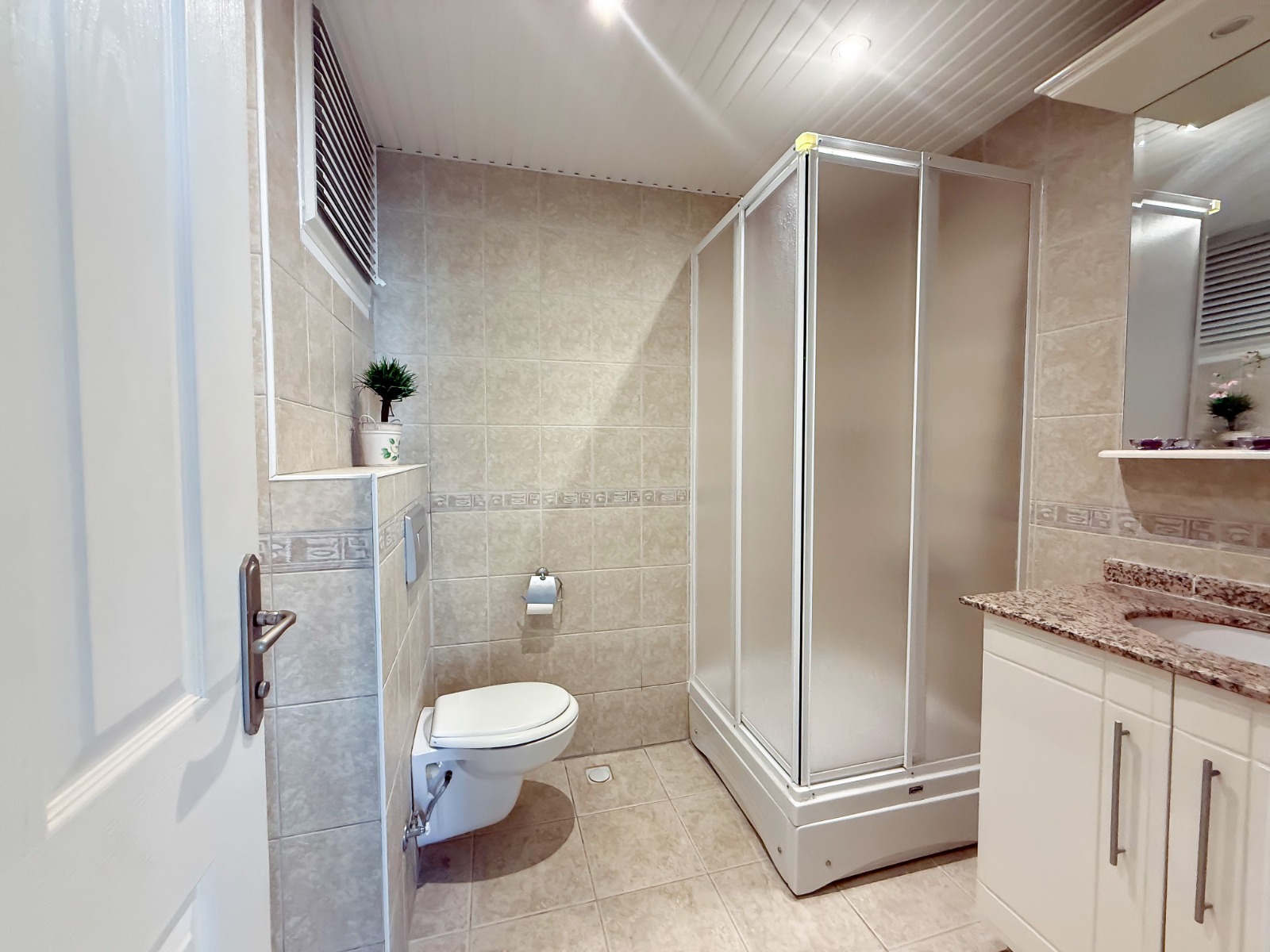 Bathroom with a shower enclosure and marble vanity in an apartment