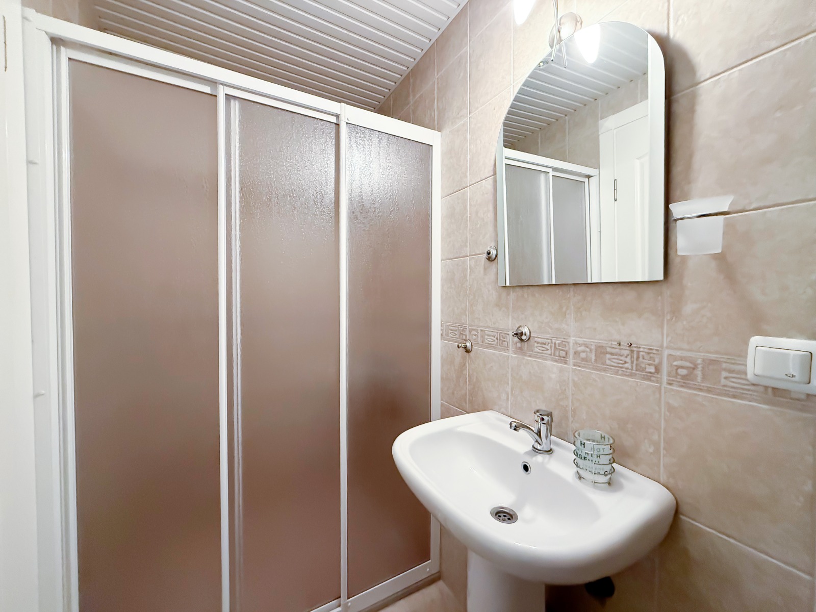 Bathroom with a shower enclosure, floor-mounted sink and wall mirror