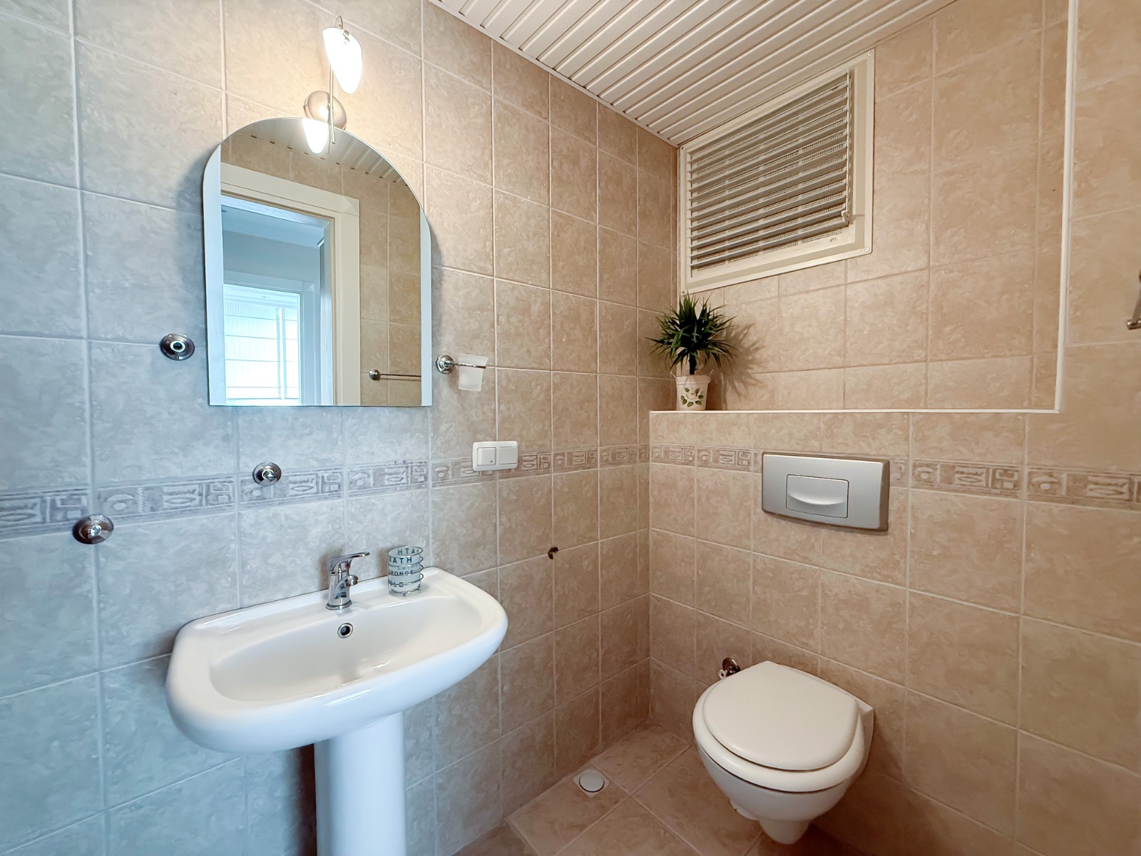 A bathroom with a floor-mounted sink and decorative border in an apartment in Mahmutlar