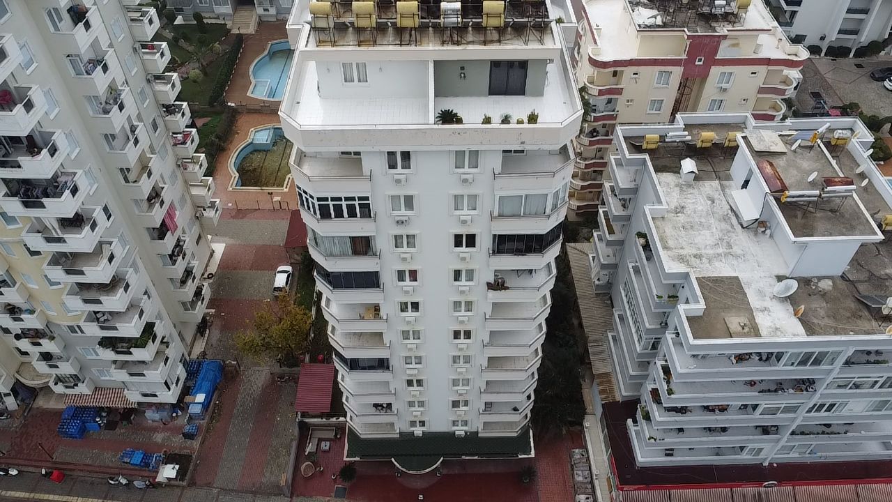 High-rise residence with balconies and a pool among neighboring buildings in Mahmutlar, Turkey