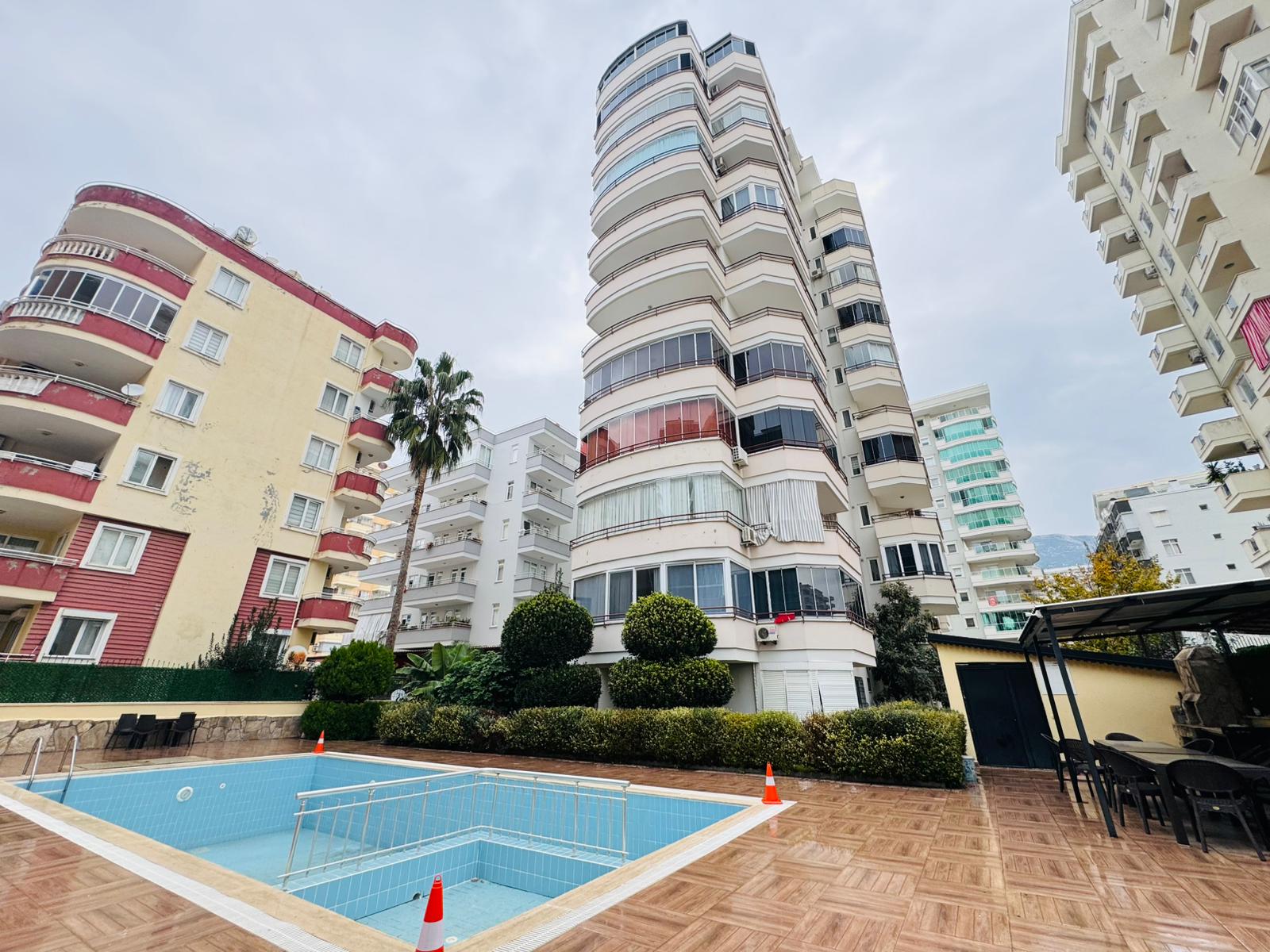 Outdoor pool with palms beside a residential building in a complex with apartments in Mahmutlar
