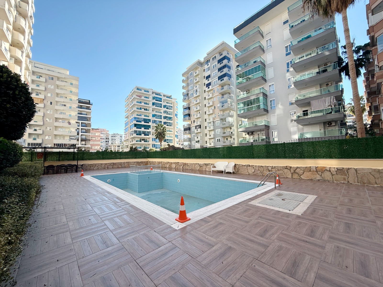 Empty rectangular pool with a metal ladder by residences where apartments are for sale in Turkey