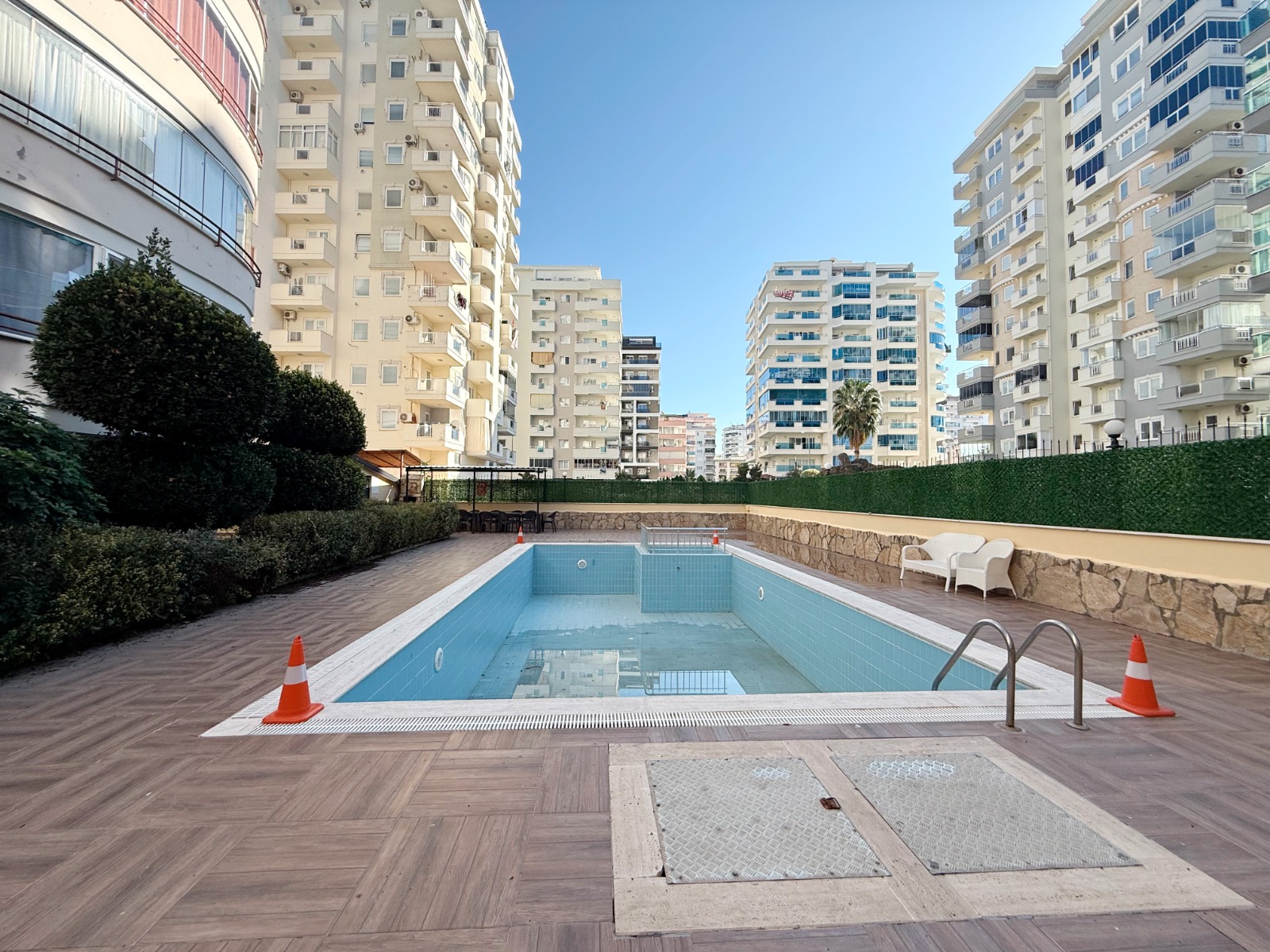 Rectangular pool with loungers and a wood-look terrace by residences where property is for sale