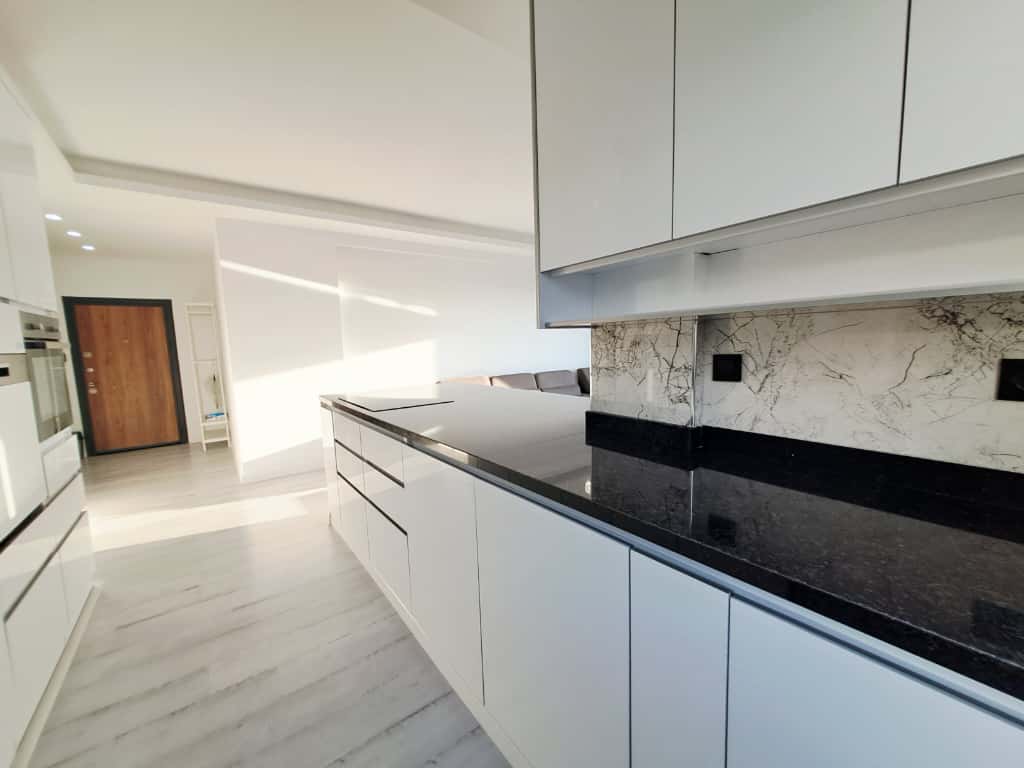 Mutfakta doğrusal beyaz dolaplar ve mermer backsplash Kargıcak’taki penthouse içinde