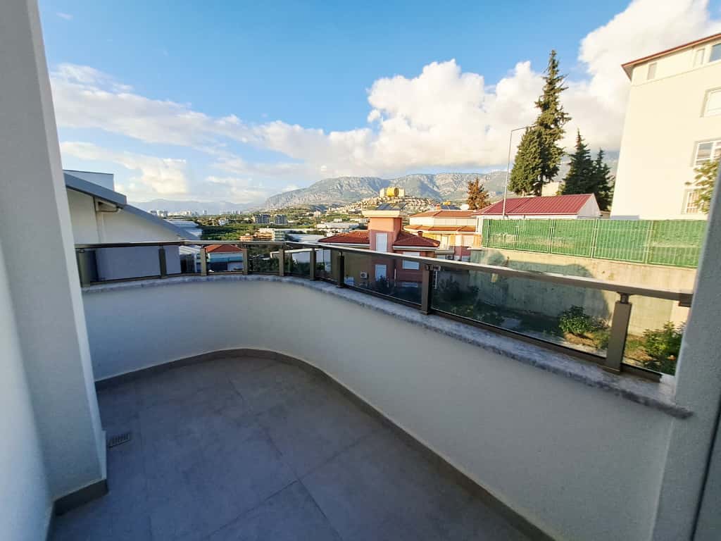 Geniş terasta cam korkuluk ve dağlara uzanan panoramik manzara çatı katı dairede