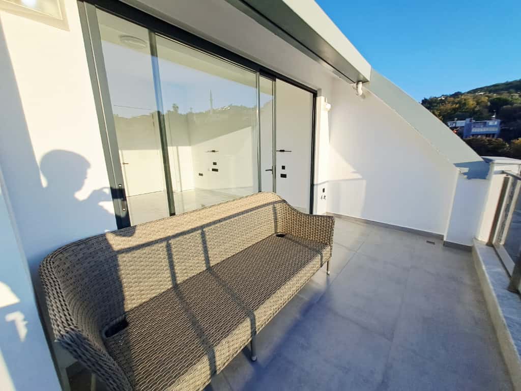 Terasta örgü koltuk ve sürgülü cam kapılar Kargıcak’taki penthouse daireden yeşil yamaca bakıyor