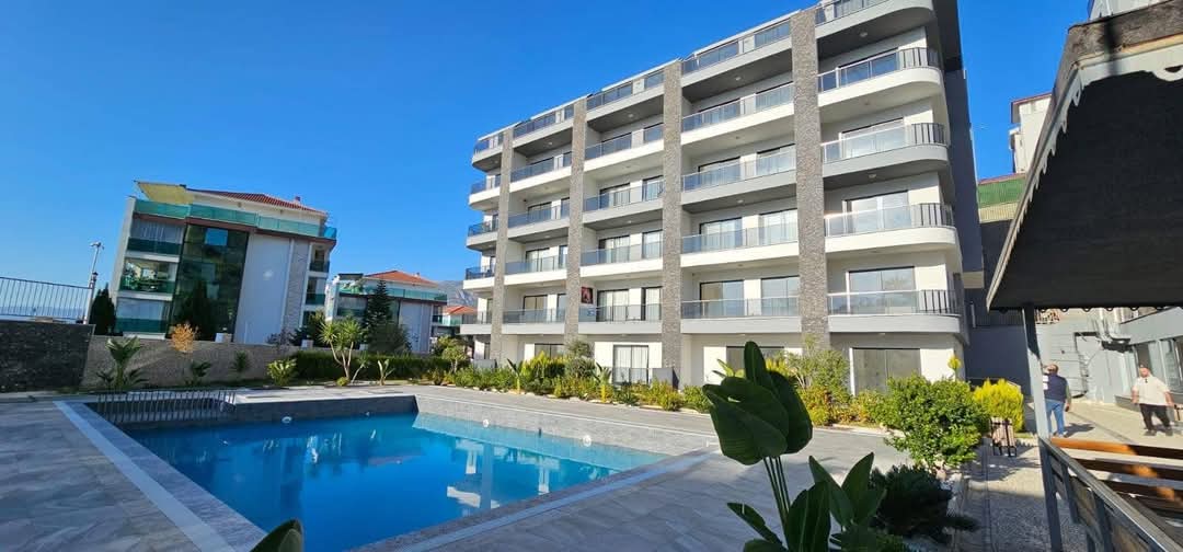 Outdoor pool beside balconies frames a 3+1 penthouse for sale in Kargicak, Alanya, Turkey — New Level Group
